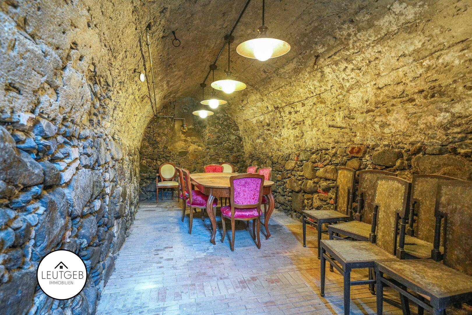 Rustikaler Kellerraum mit Steinmauern, Gewölbedecken und Esstisch.