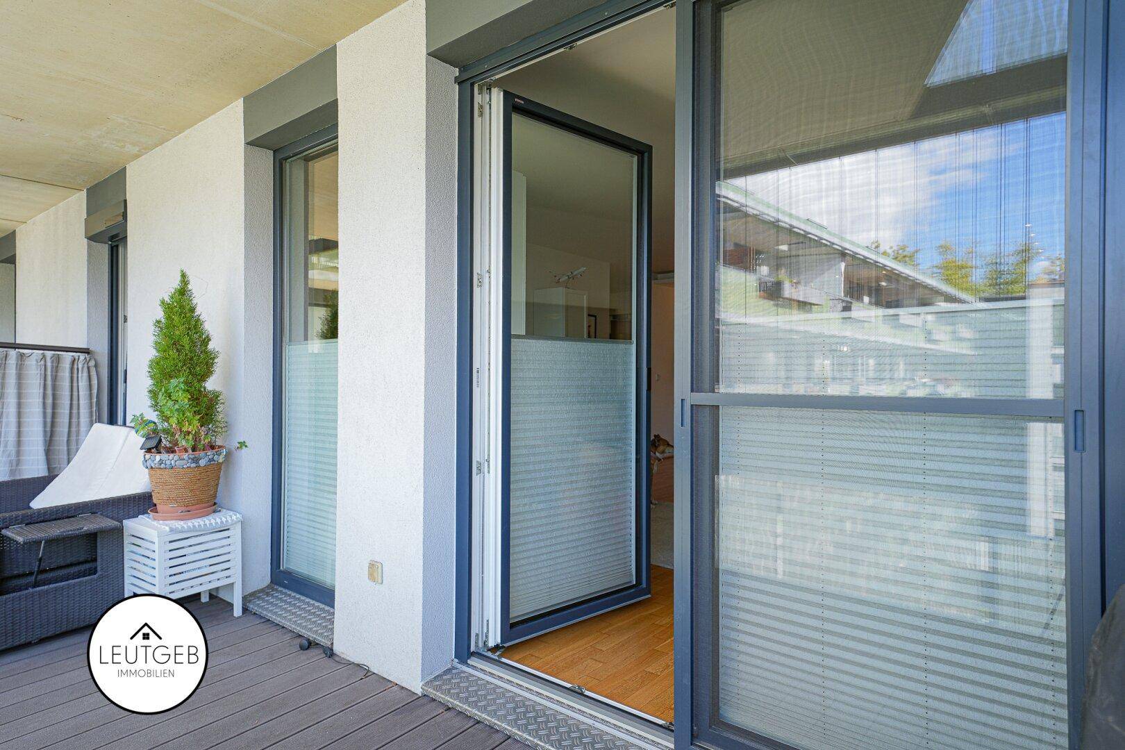 Balkon mit Holzboden und Schiebetür, der Zugang zum Innenbereich bietet.