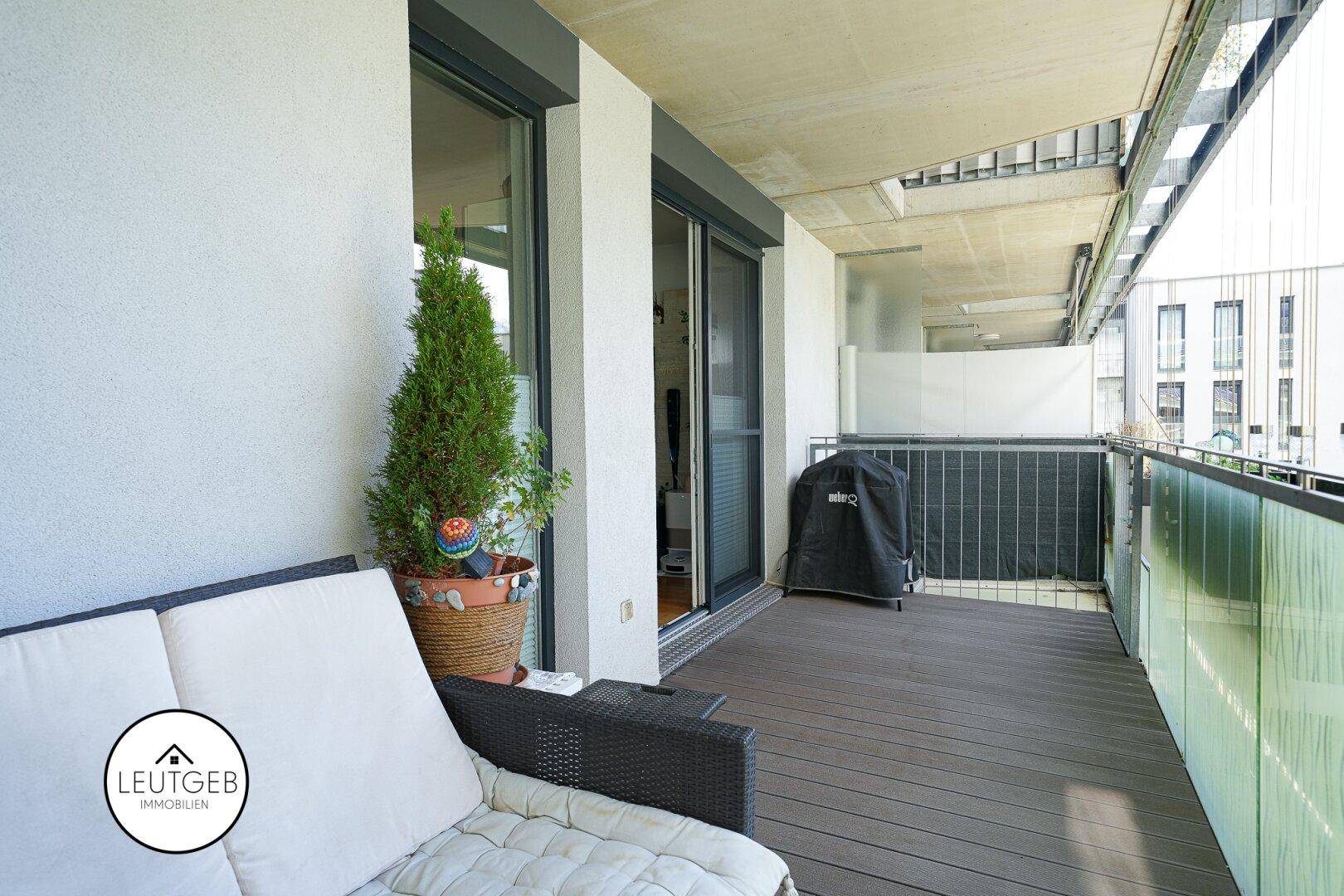 Geräumiger Balkon mit Sitzgelegenheiten, Pflanzen und Grill, ideal für entspannte Stunden.
