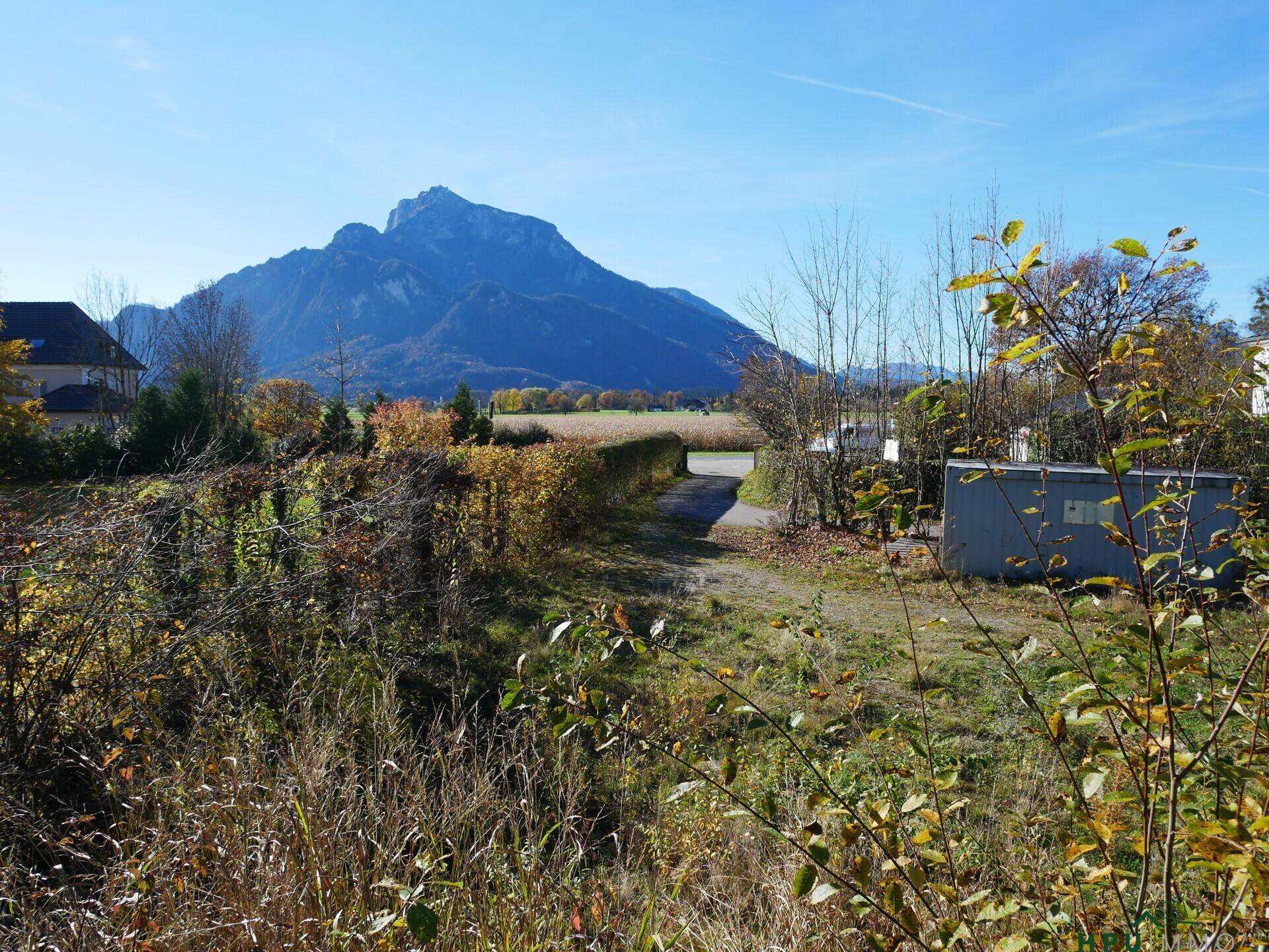 Panoramablick auf die Berglandschaft mit Feldern und herbstlichen Bäumen an einem sonnigen Tag.