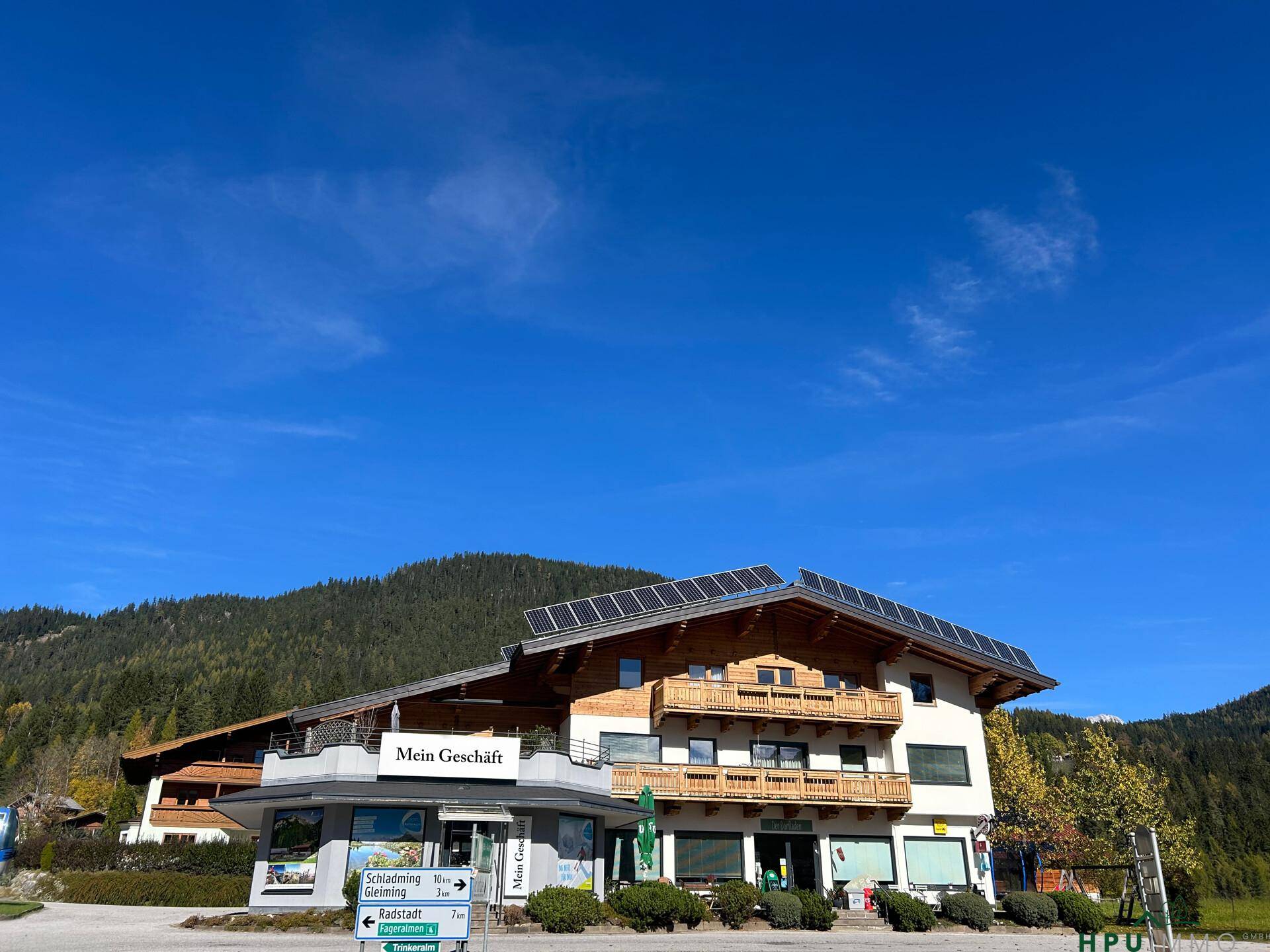 Weitläufige Außenansicht des Gebäudes mit Solaranlage unter strahlend blauem Himmel.