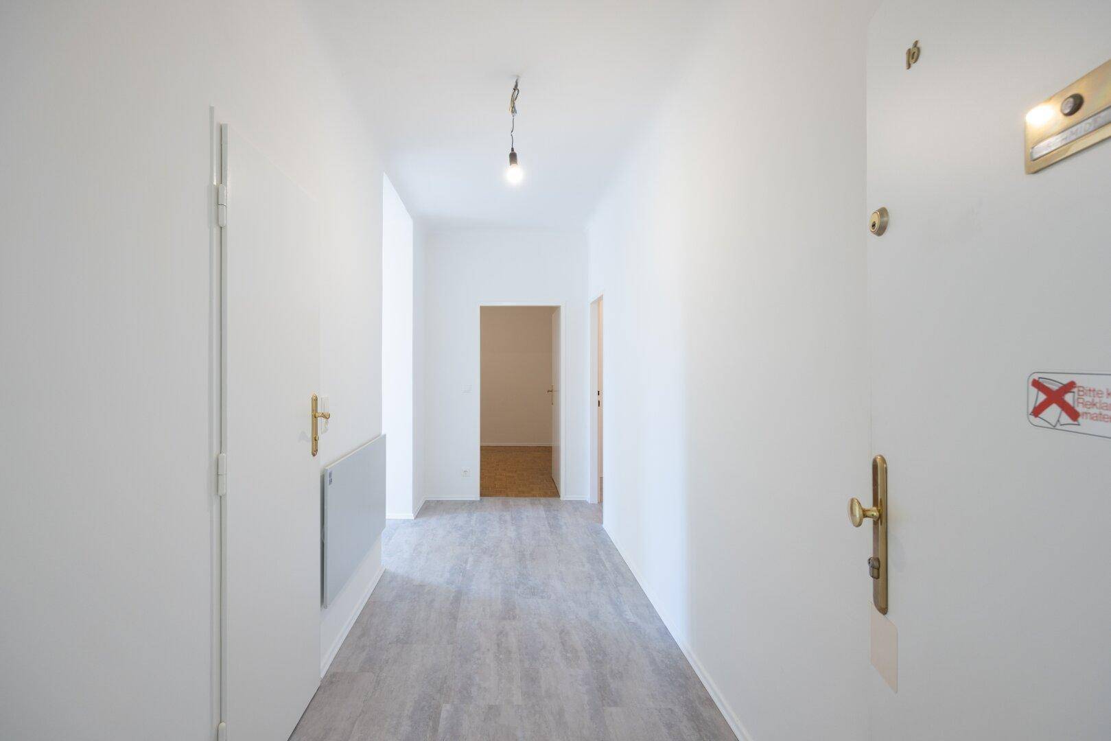 Heller, leerer Flur einer Wohnung mit frisch gestrichenen Wänden und modernem Vinylboden.