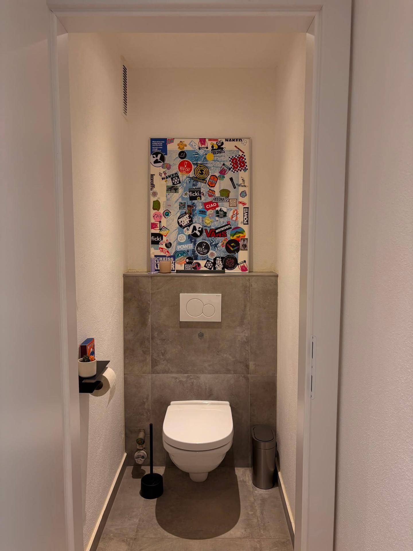 Modernes Gäste-WC mit Wand-WC und grauen Fliesen an Wand und Boden.
