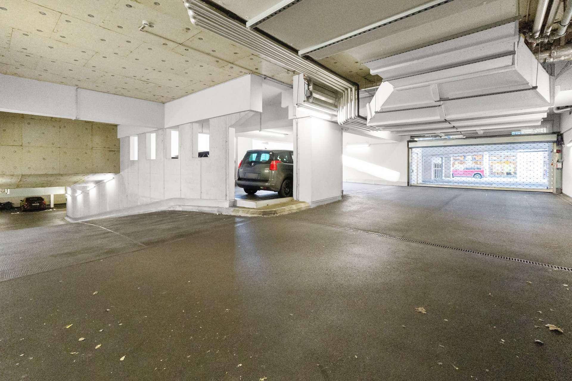 Ausgang einer Tiefgarage mit Rolltor und Betonwänden.