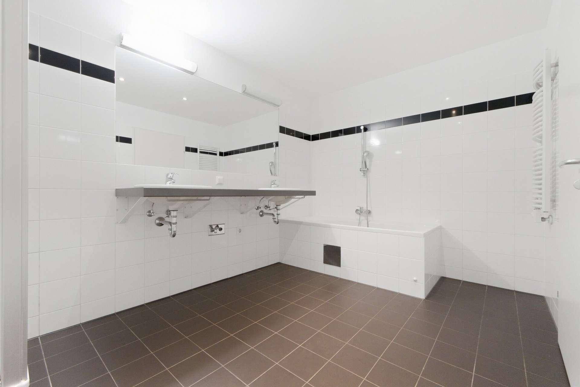 Geräumiges Badezimmer mit Badewanne, Doppelwaschbecken und beheiztem Handtuchhalter.
