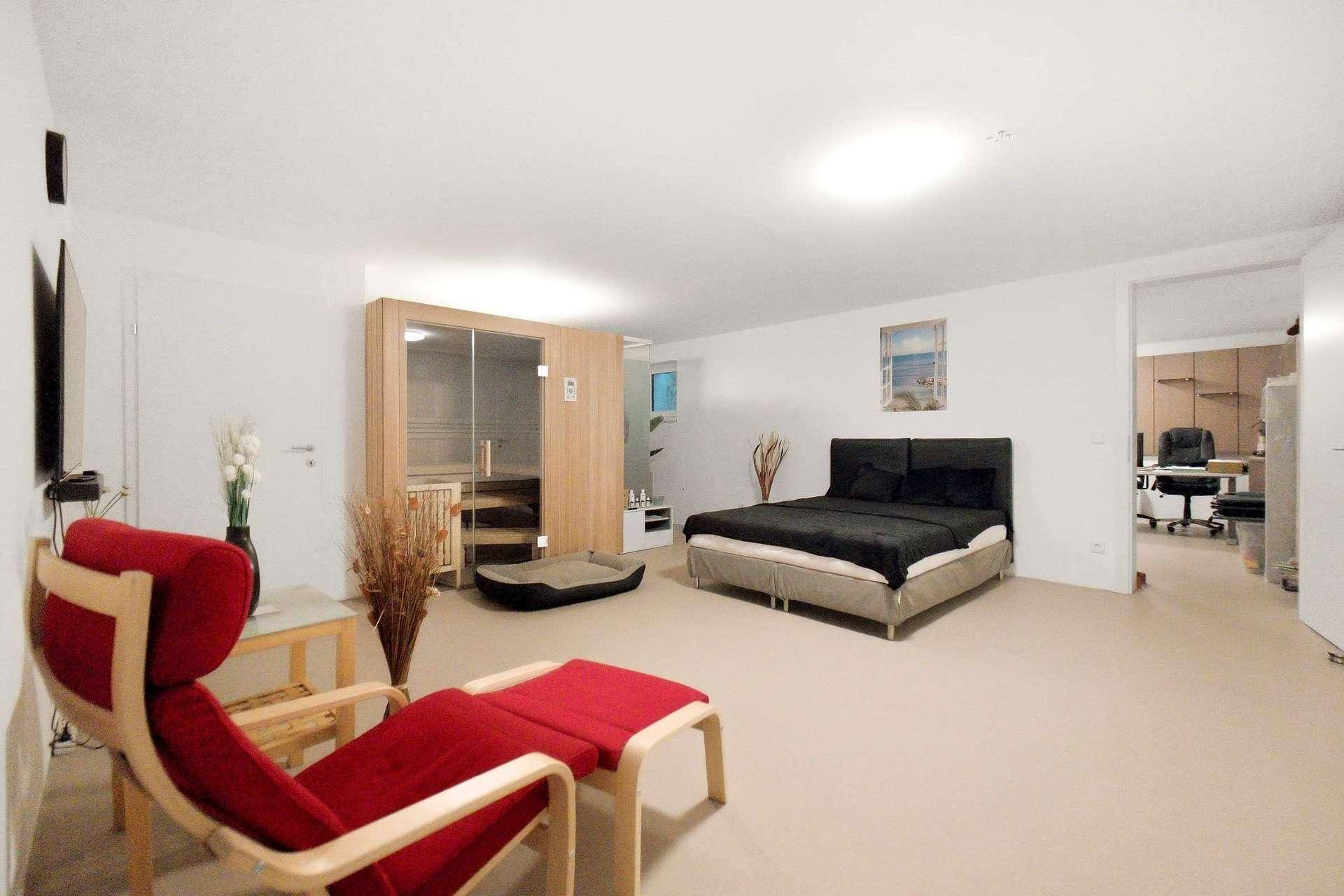 Großzügiges Schlafzimmer mit Doppelbett, Sessel und integrierter Sauna.