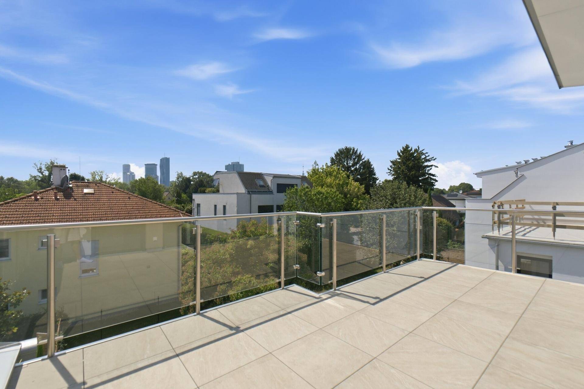 Geräumige Dachterrasse mit Glasgeländer und weitem Blick auf die Stadt und Umgebung.