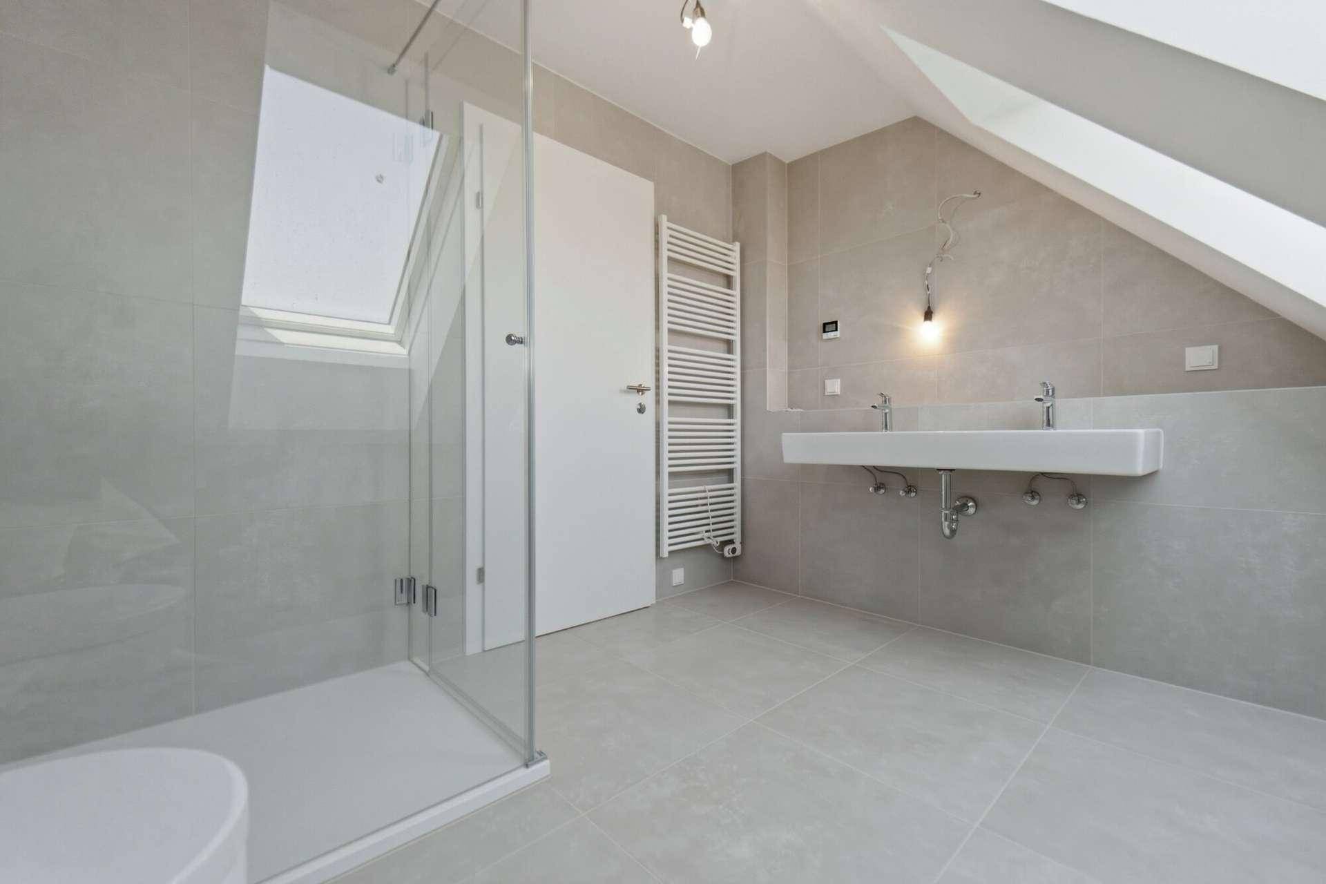 Modernes Badezimmer im Dachgeschoss mit Doppelwaschbecken, begehbarer Dusche und Dachfenster.