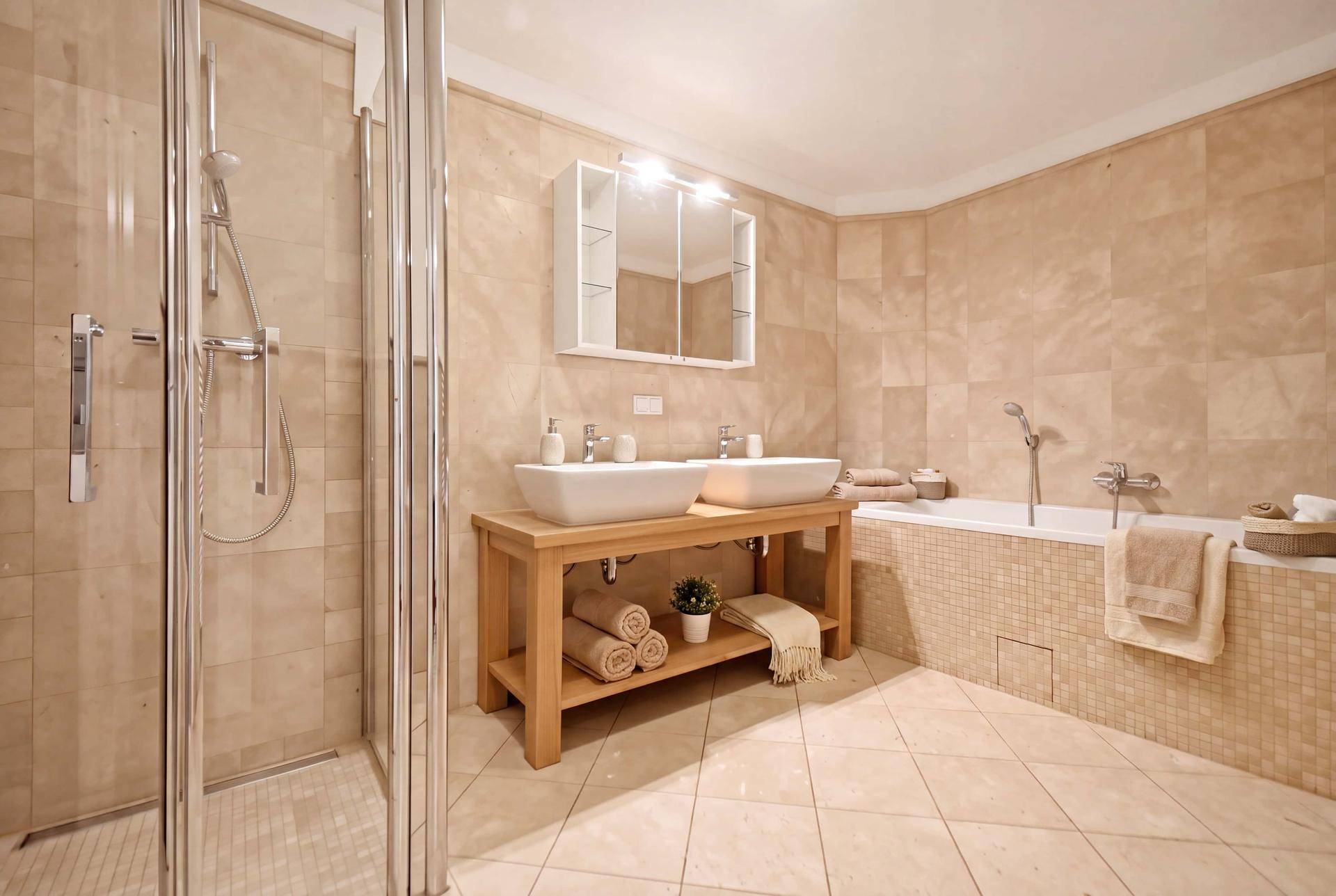 Modernes Badezimmer mit Doppelwaschbecken, Dusche und Badewanne, hell gefliest.