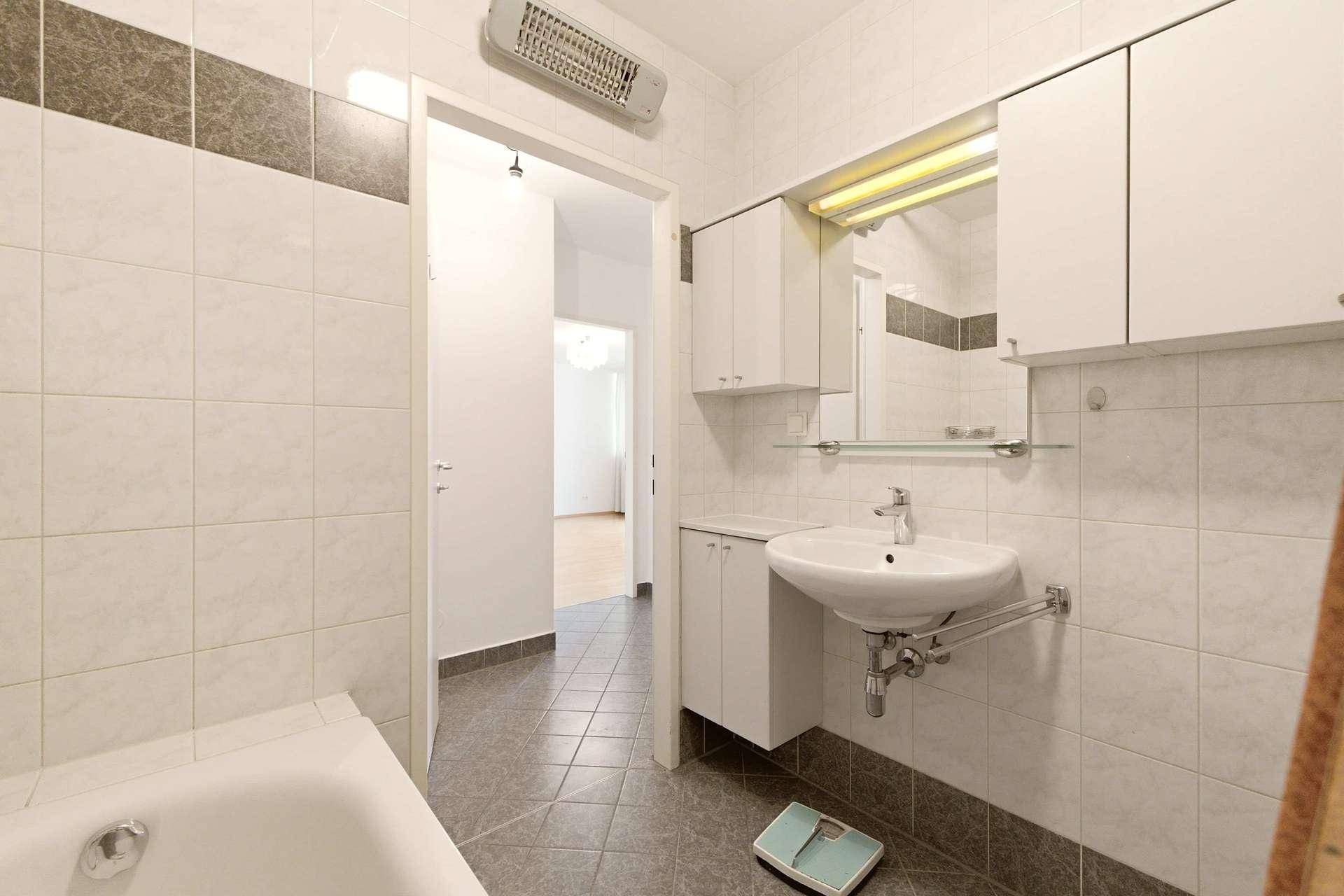 Badezimmer mit Waschbecken, Spiegelschrank und offenem Zugang zum angrenzenden Flur.