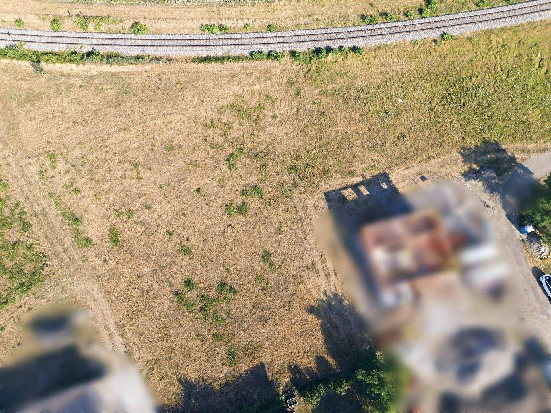 Luftaufnahme eines Grundstücks mit angrenzenden Bahngleisen und weiten Feldern.