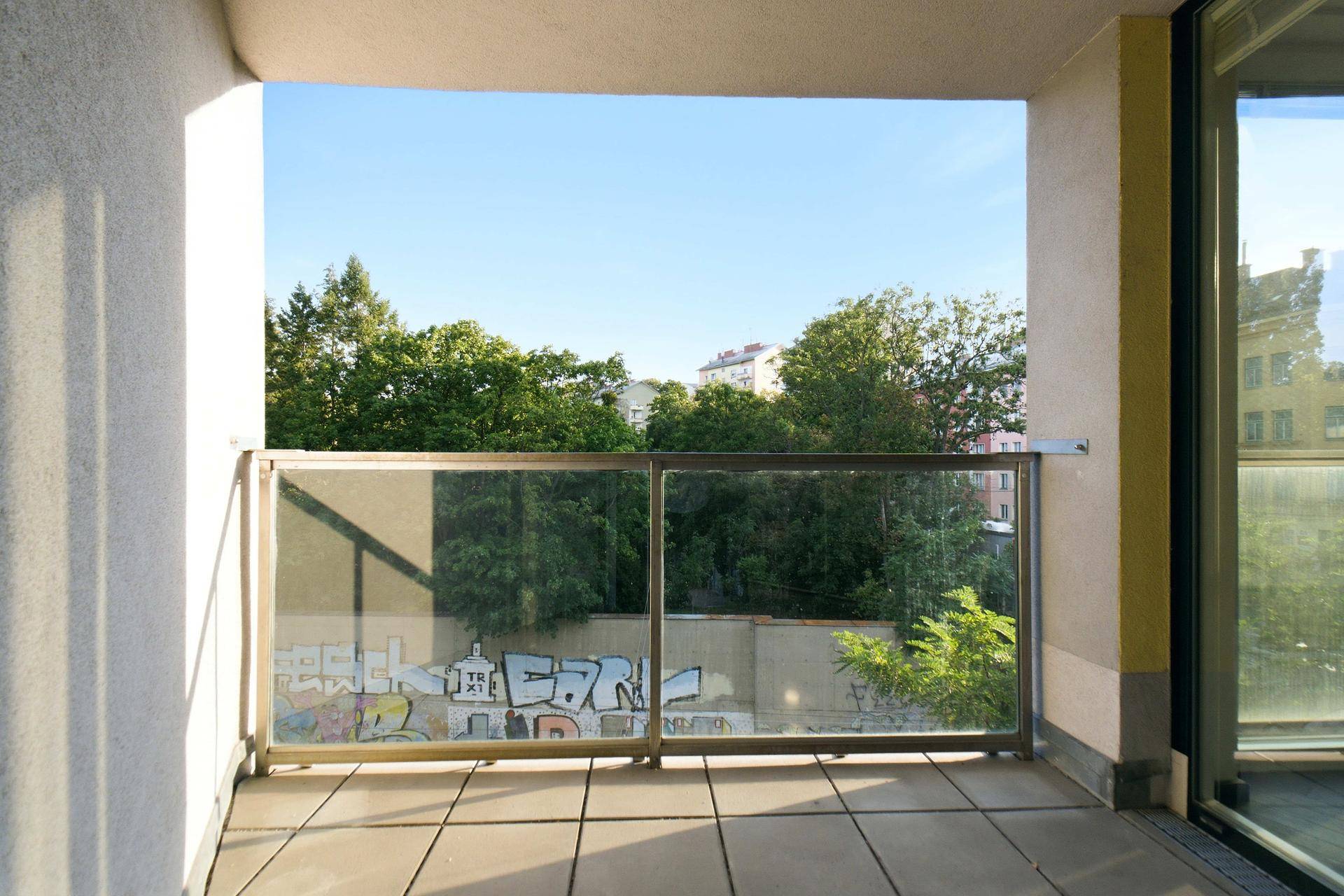 Geräumiger Balkon mit Fliesenboden und Glasgeländer, bietet einen weiten Blick auf die Umgebung.