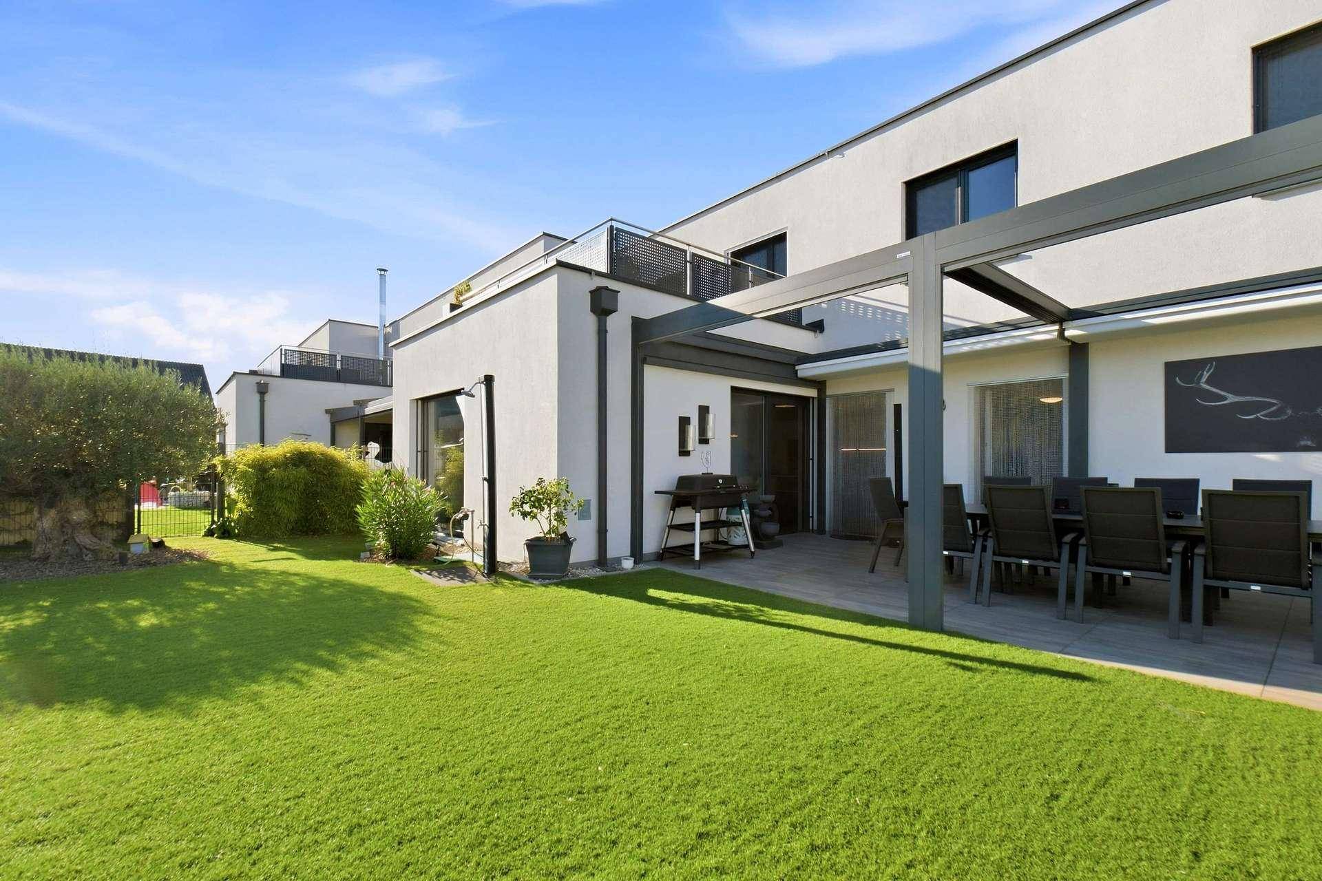 Moderner Neubau mit großem Garten und überdachtem Terrassenbereich.
