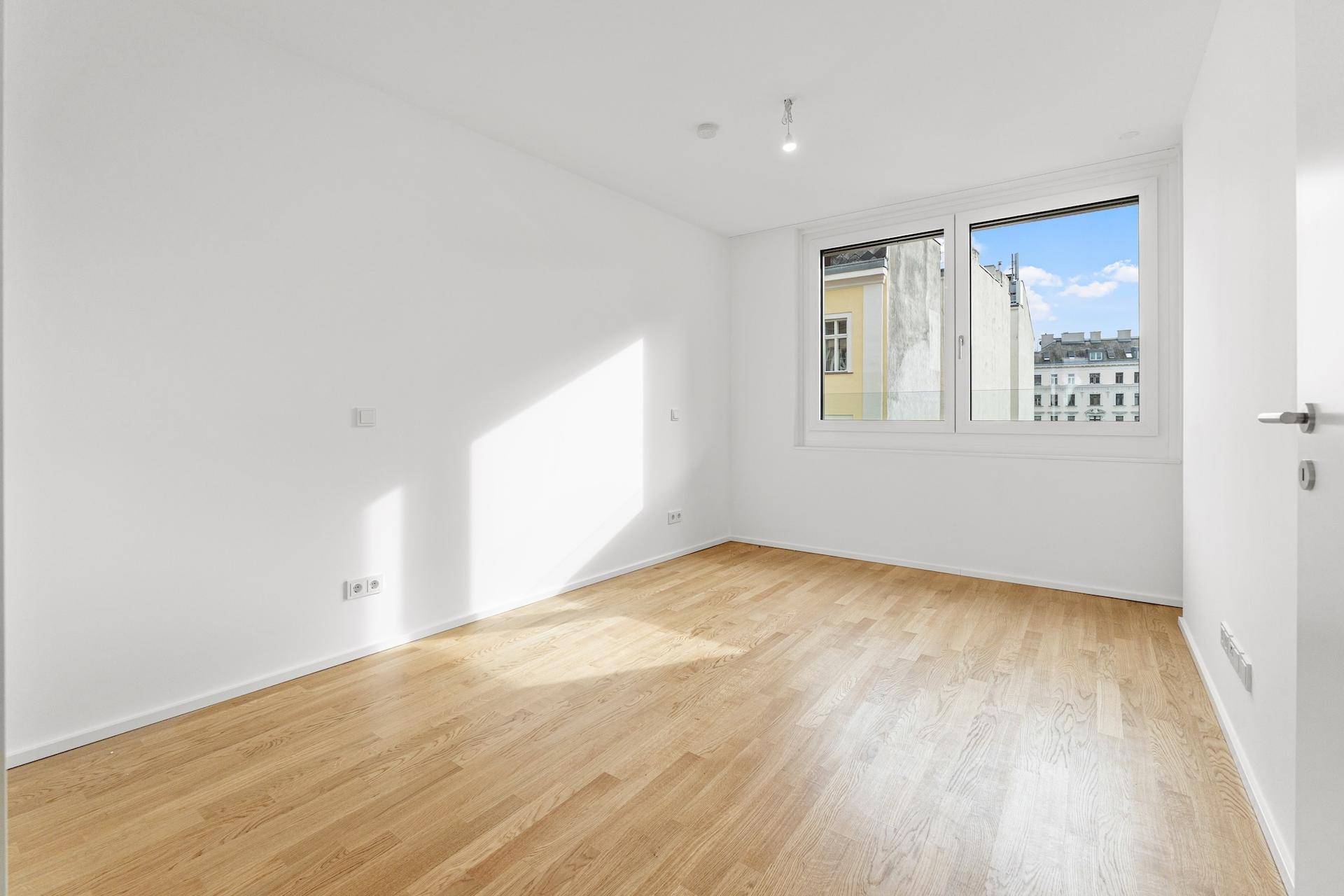 Helles Schlafzimmer mit Holzboden und großem Fenster für viel Tageslicht.