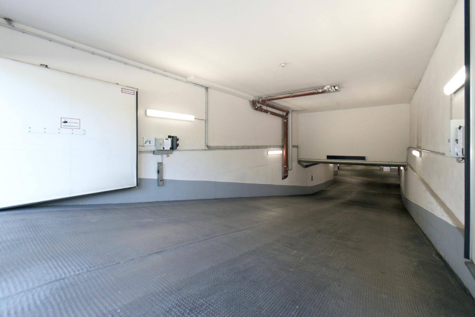 Zufahrt zur Tiefgarage mit automatischer Tür und rutschfestem Bodenbelag.