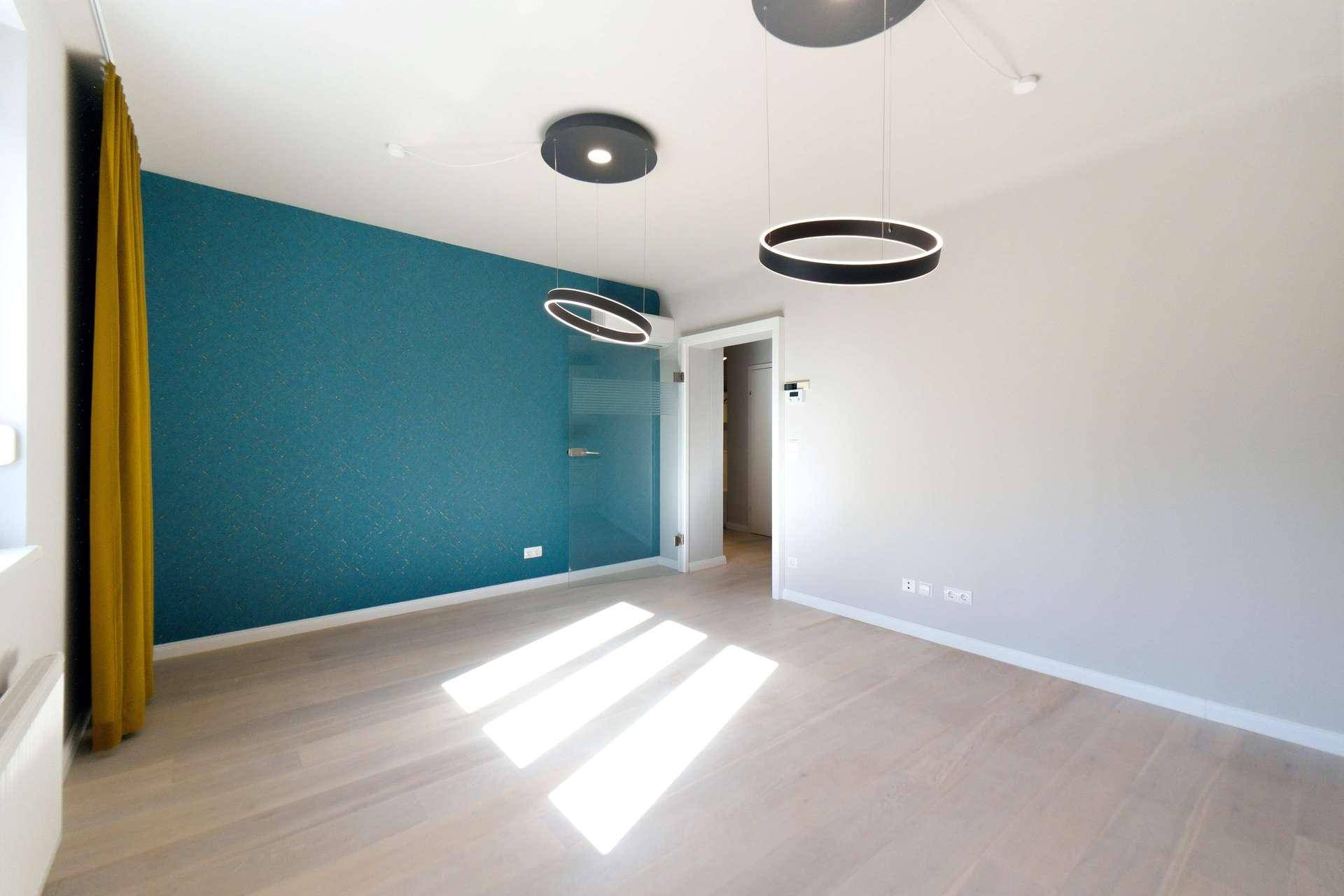Modernes Wohnzimmer mit blauer Akzentwand, hellem Boden und stilvoller Glastür.