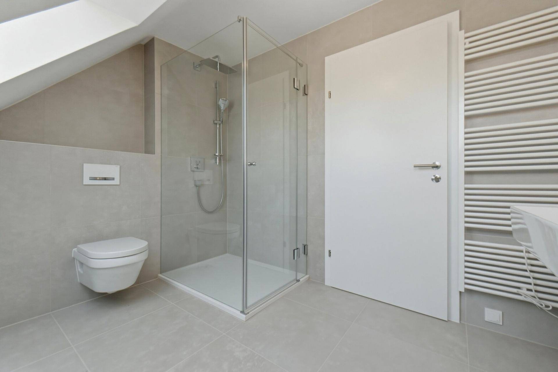 Modernes Badezimmer mit begehbarer Dusche, Hänge-WC und Dachschräge, in hellen Grautönen gehalten.