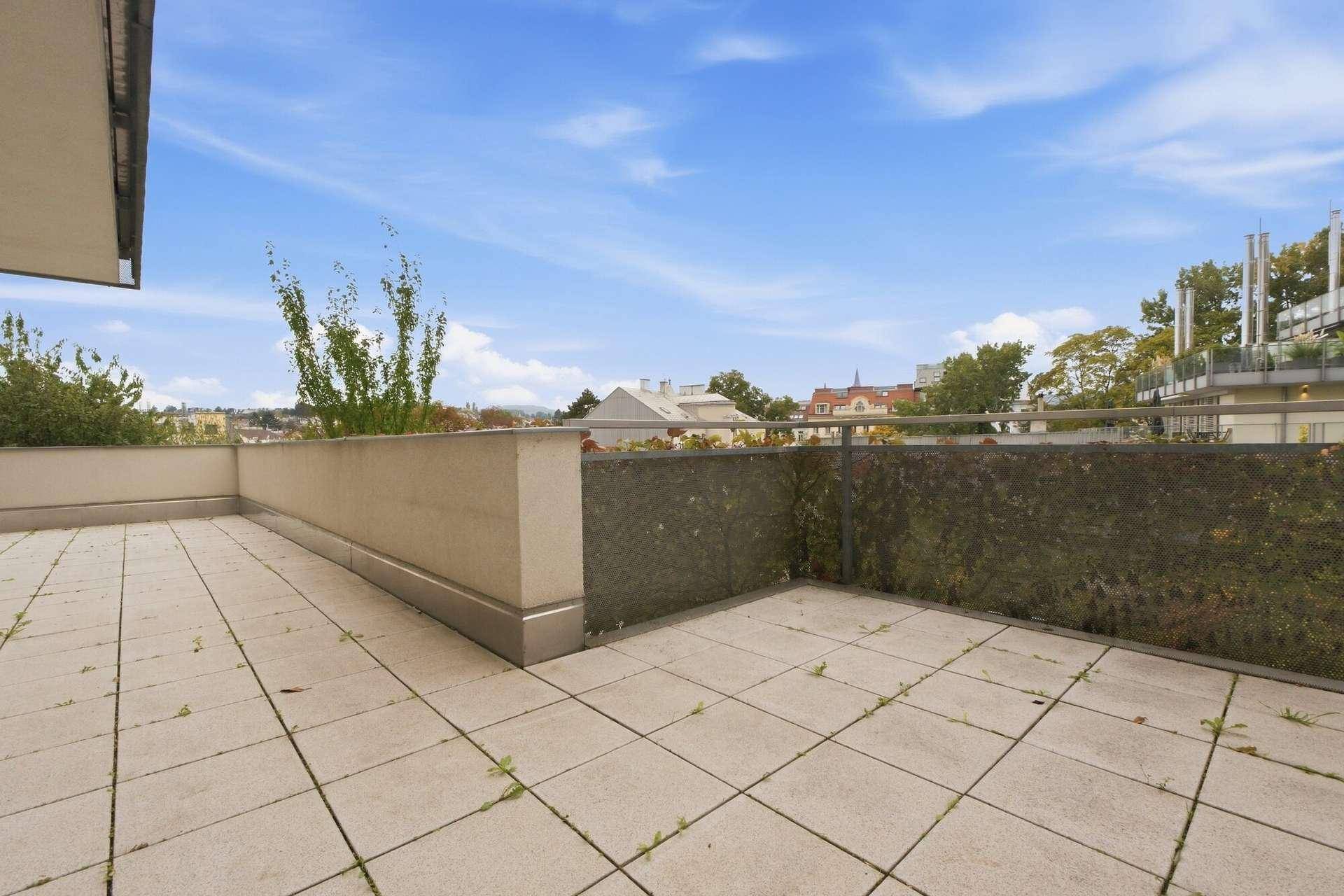 Große Terrasse mit Fliesenboden und Panoramablick über die Stadt und grüne Umgebung.