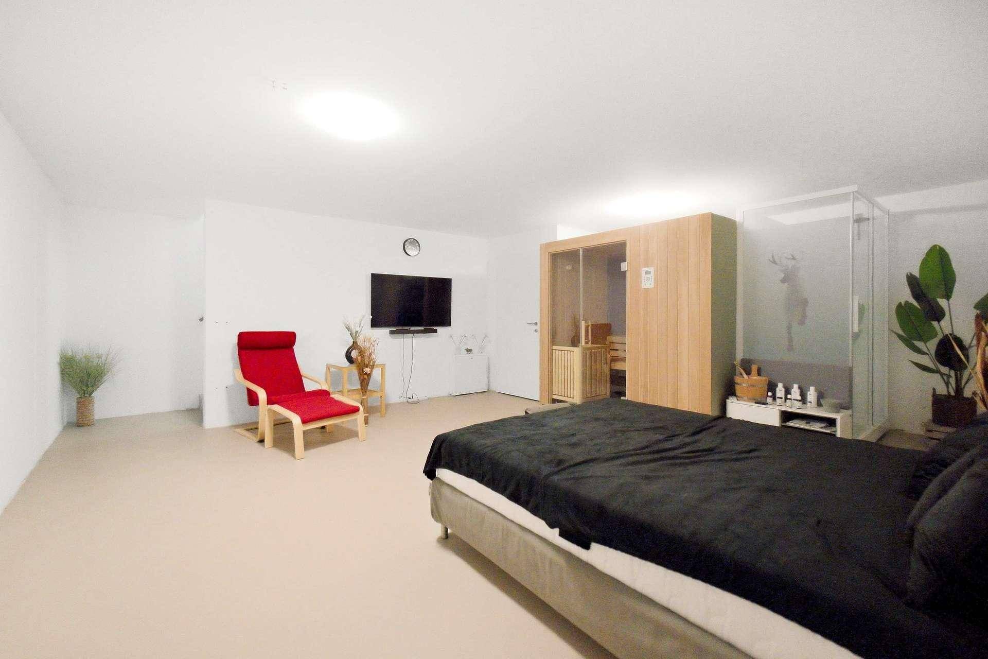 Modernes Schlafzimmer mit Doppelbett, Fernseher und privater Sauna.