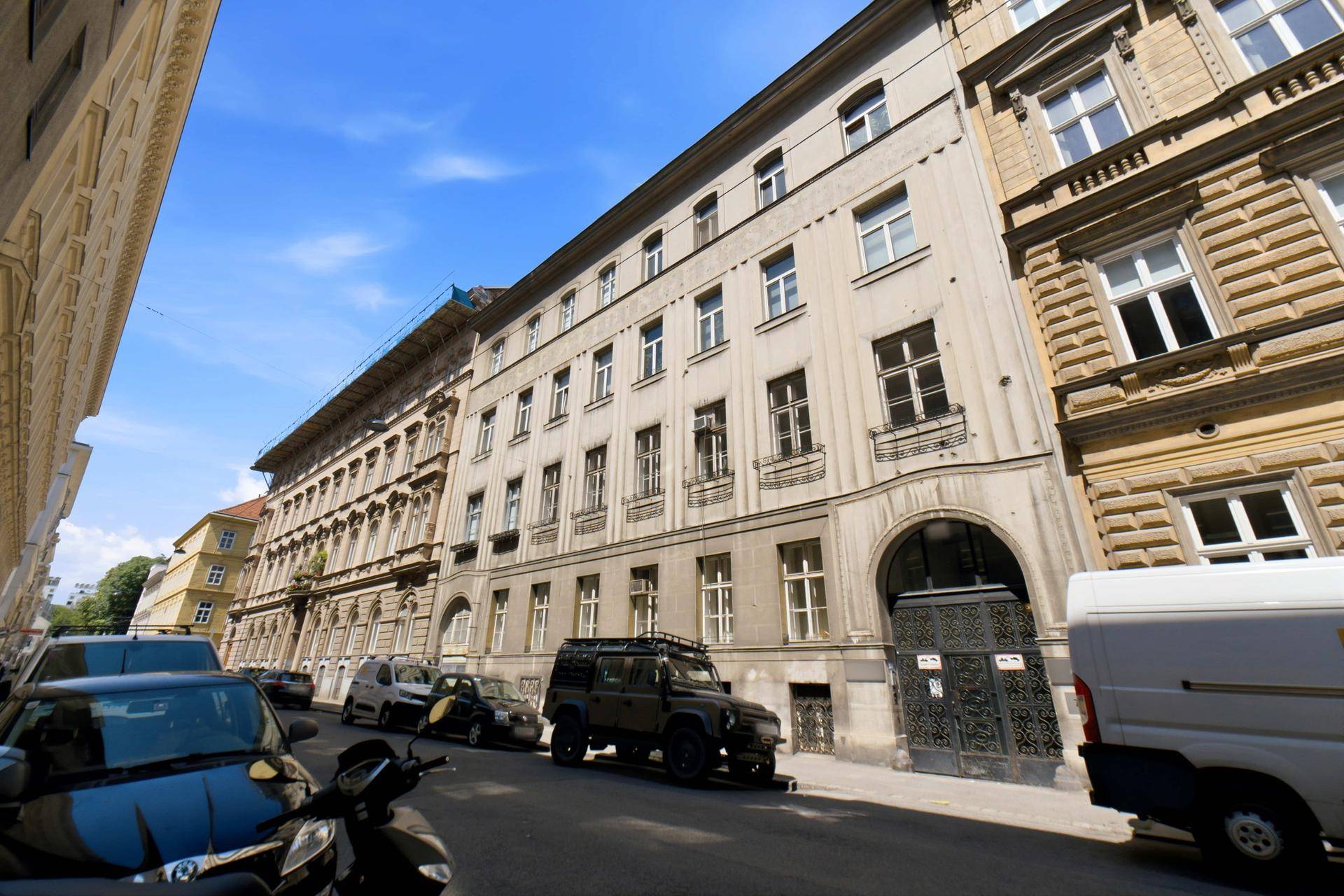 Historisches Gebäude mit klassischer Fassade und vielen Fenstern an einer belebten Straße.