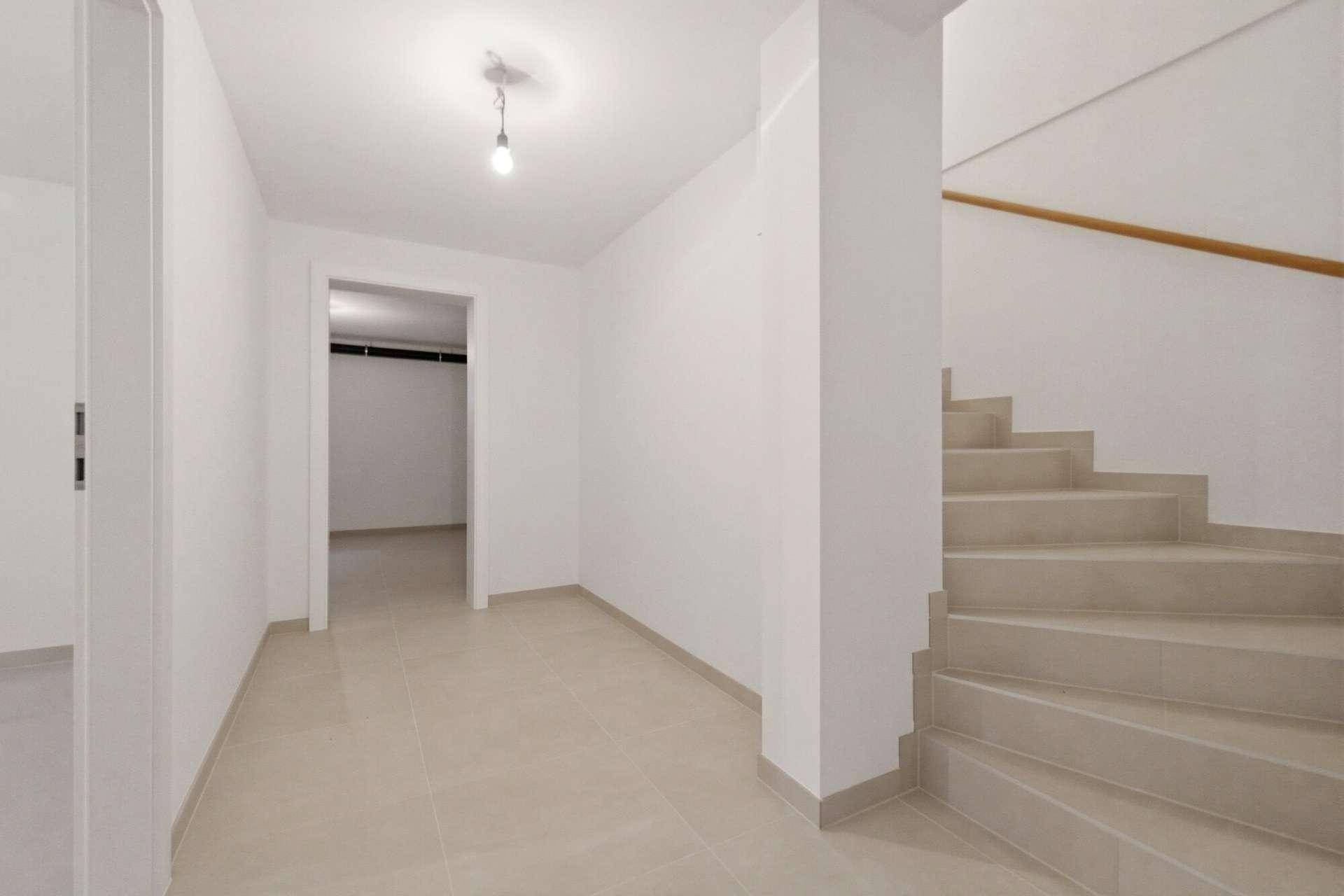 Heller Flur mit Fliesenboden und Treppe, die zu den oberen Etagen führt.