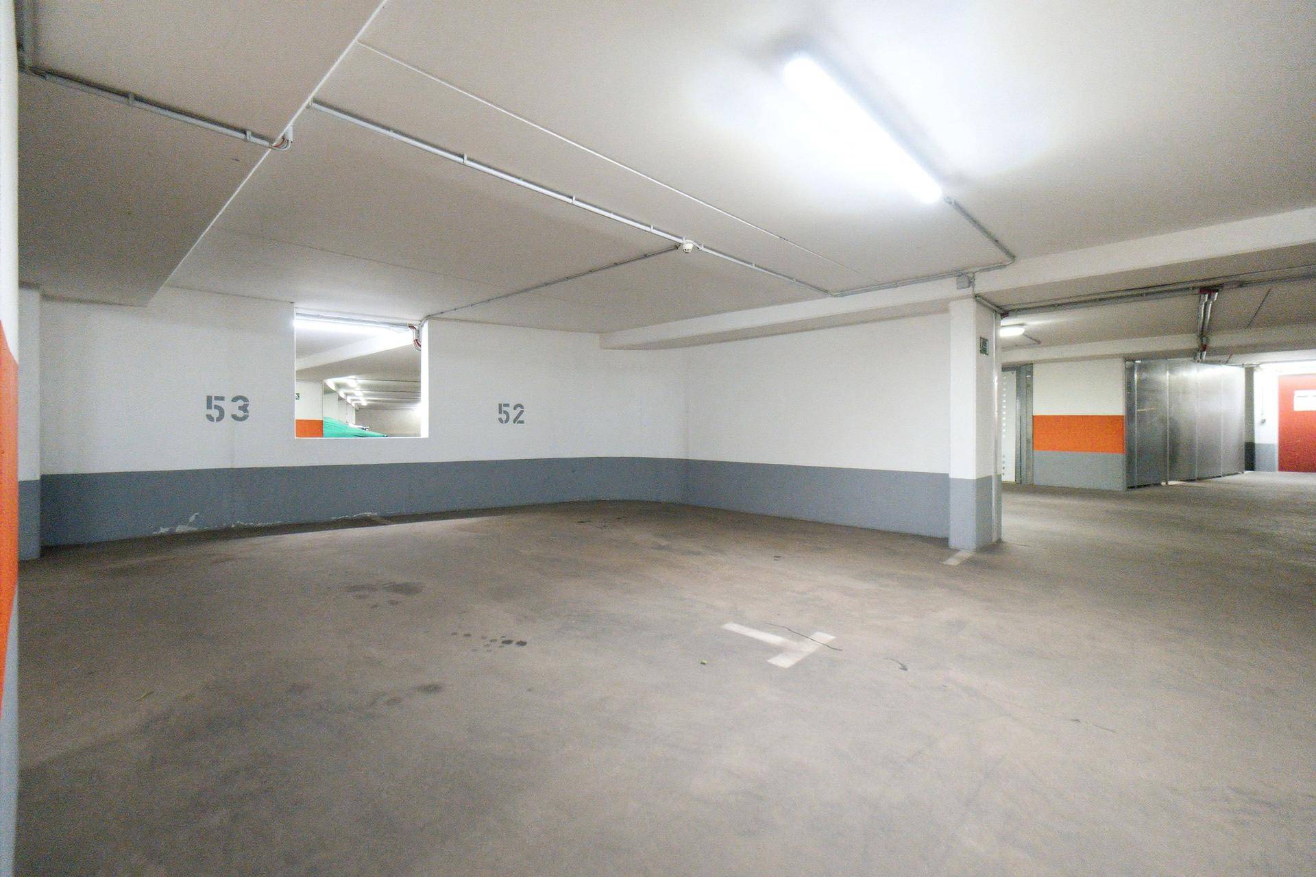Leerer Stellplatz in der Tiefgarage mit Betonboden und nummerierten Wänden.