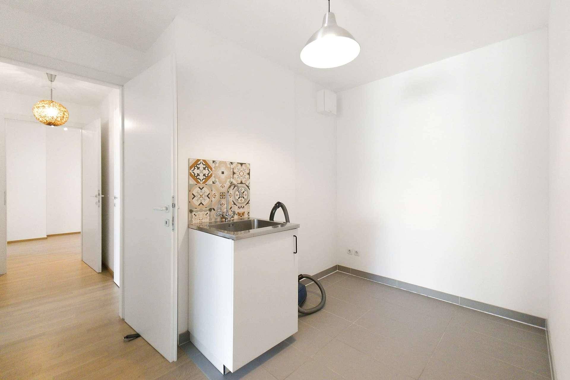 Heller Hauswirtschaftsraum mit Spülbecken und Fliesenboden.
