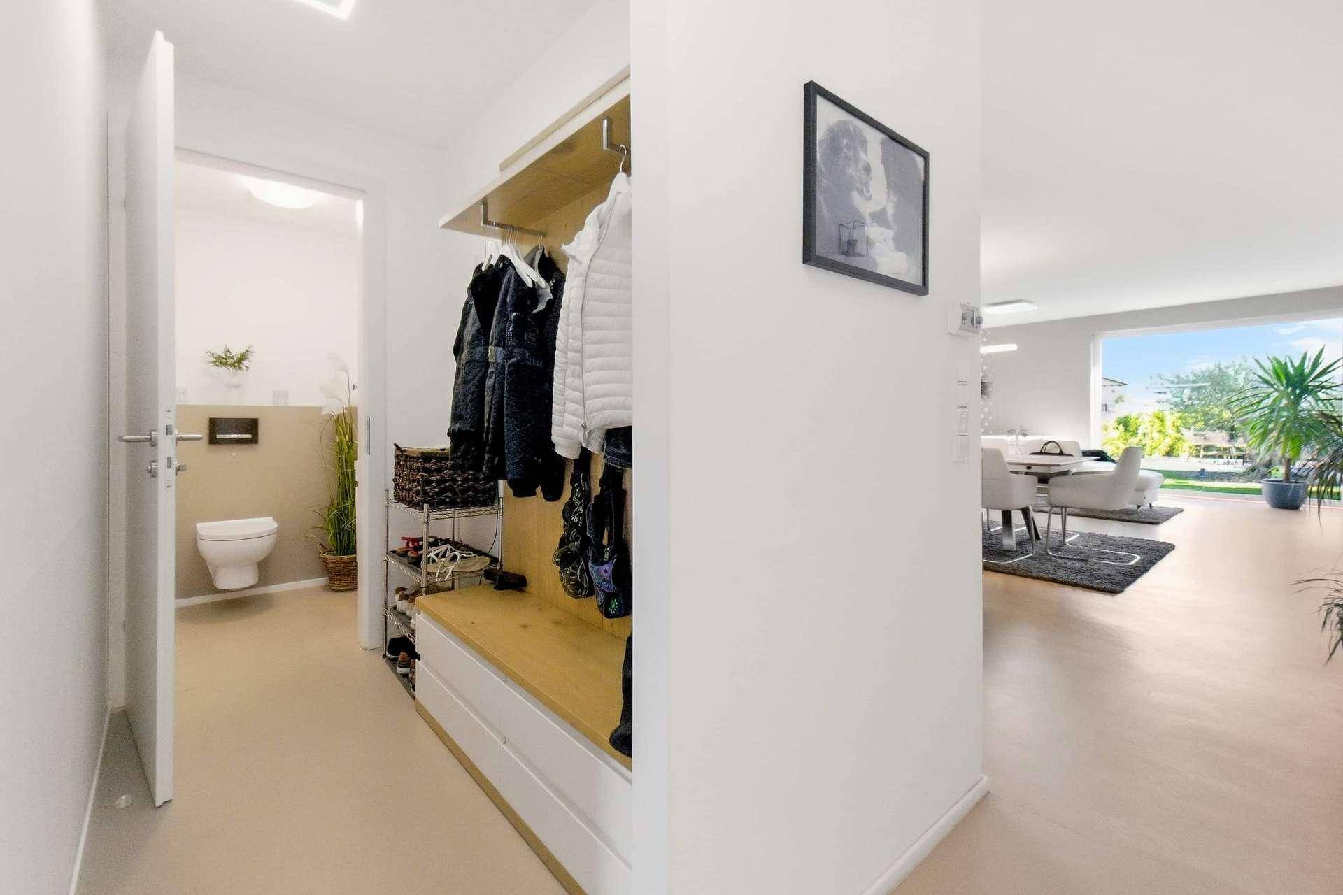 Eingangsbereich mit Garderobe und Blick auf das moderne Gäste-WC.