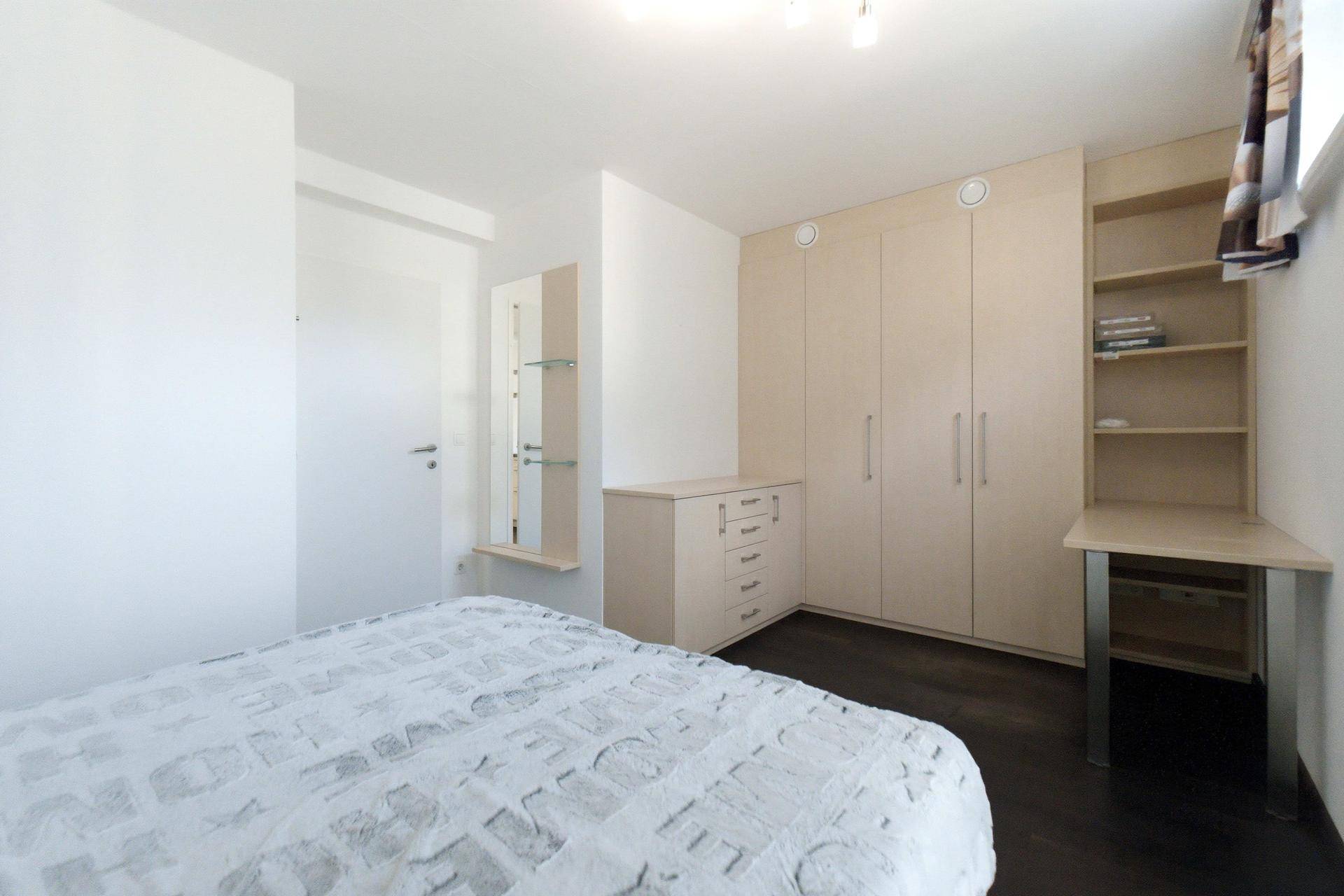 Schlafzimmer mit Einbauschränken, Kommode und Spiegel, bietet viel Stauraum und helle Einrichtung.