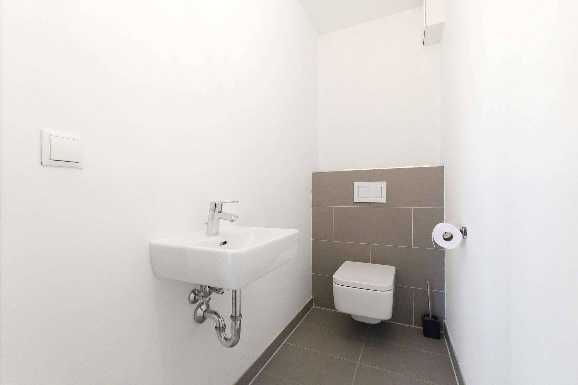 Kleines Gäste-WC mit wandhängender Toilette und modernem Waschbecken.