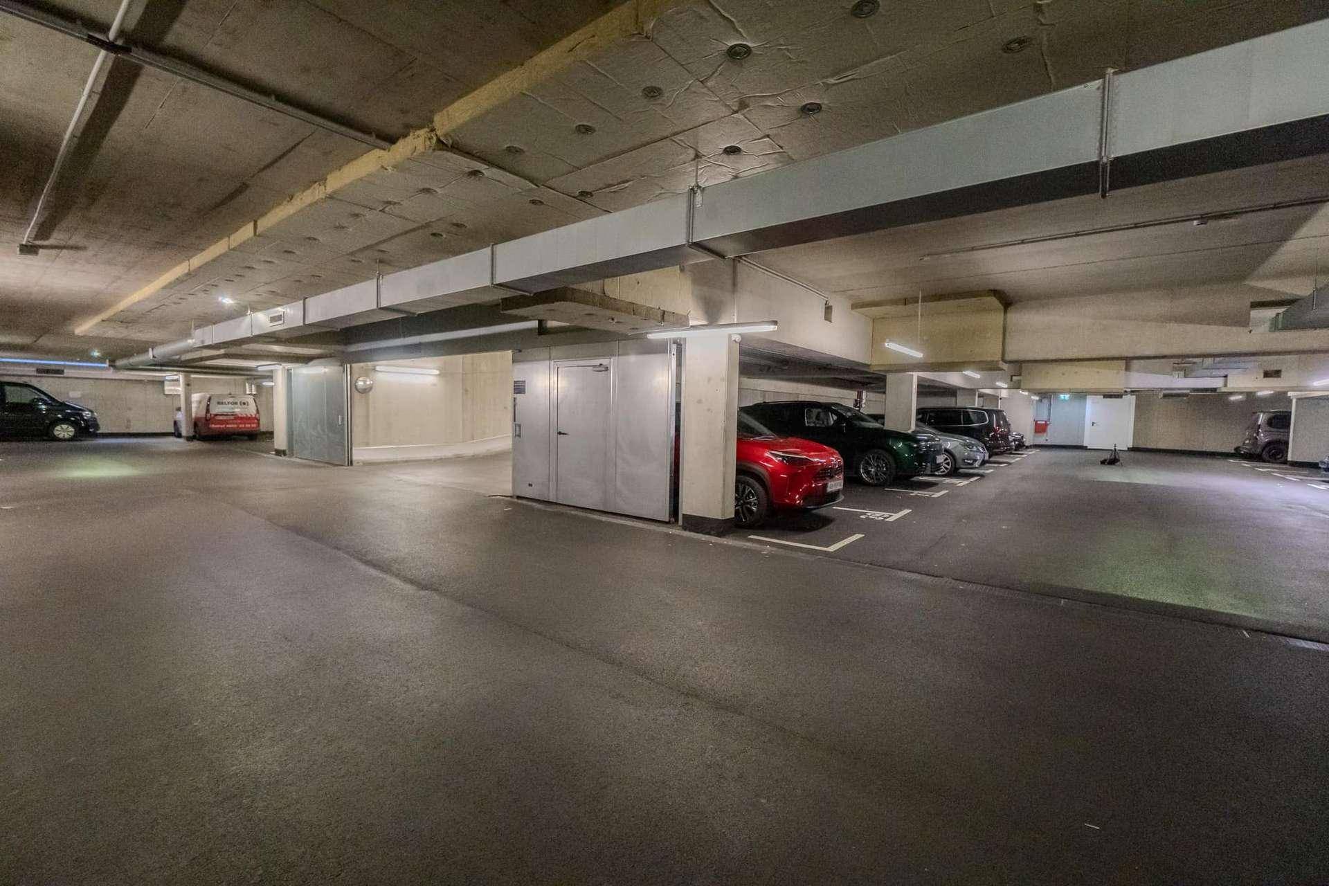 Tiefgarage mit mehreren geparkten Fahrzeugen und Betonkonstruktion.