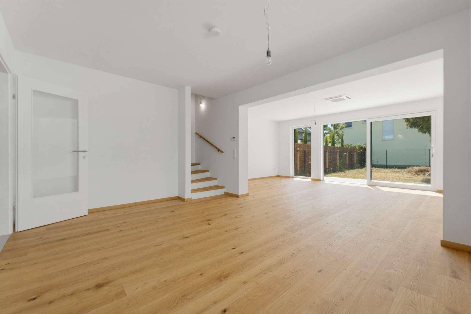 Helles Wohnzimmer mit Holzboden und großen Schiebetüren zum Garten, viel Tageslicht.