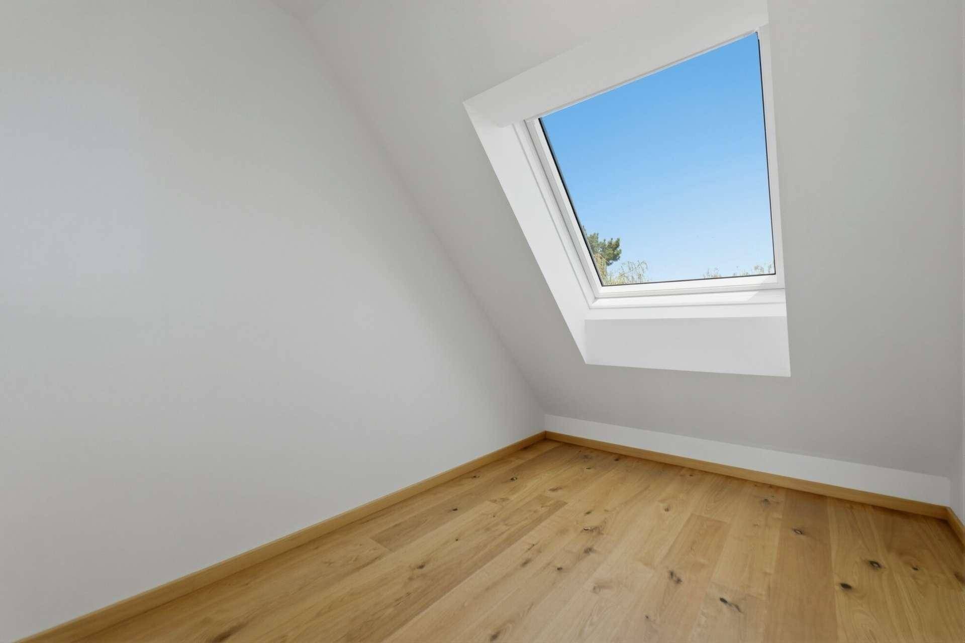 Heller Raum im Dachgeschoss mit Holzboden und Dachfenster, ideal für ein kleines Büro oder Abstellraum.