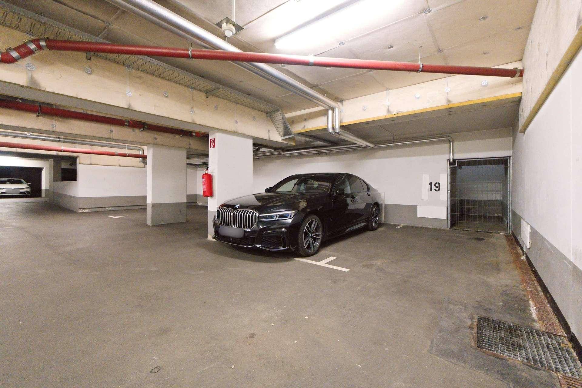 Tiefgarage mit einem geparkten Auto und nummerierten Stellplätzen.