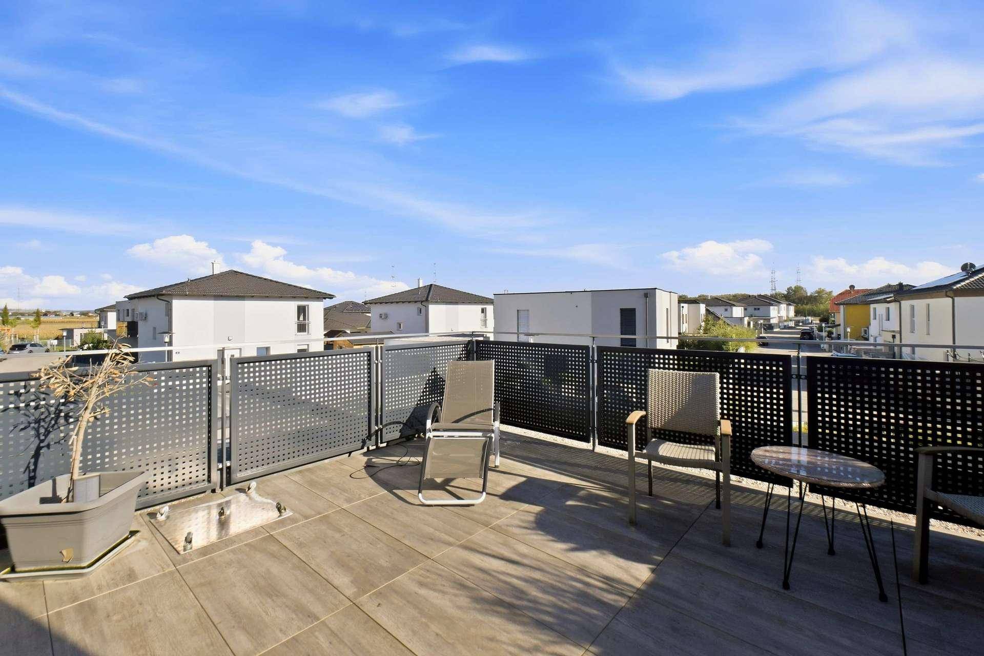 Geräumige Dachterrasse mit modernen Möbeln und weitem Blick über die Nachbarschaft.