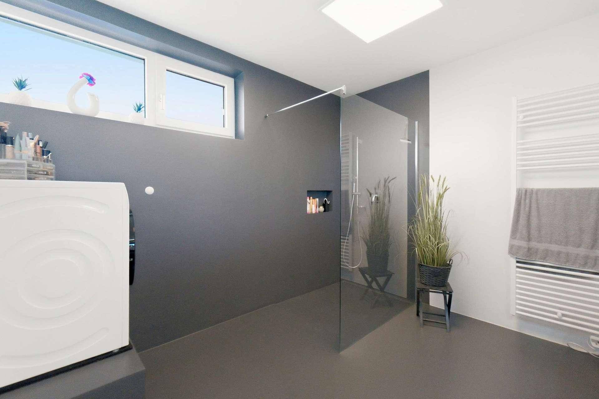 Modernes Badezimmer mit ebenerdiger Dusche, Waschmaschine und Fenster für Tageslicht.