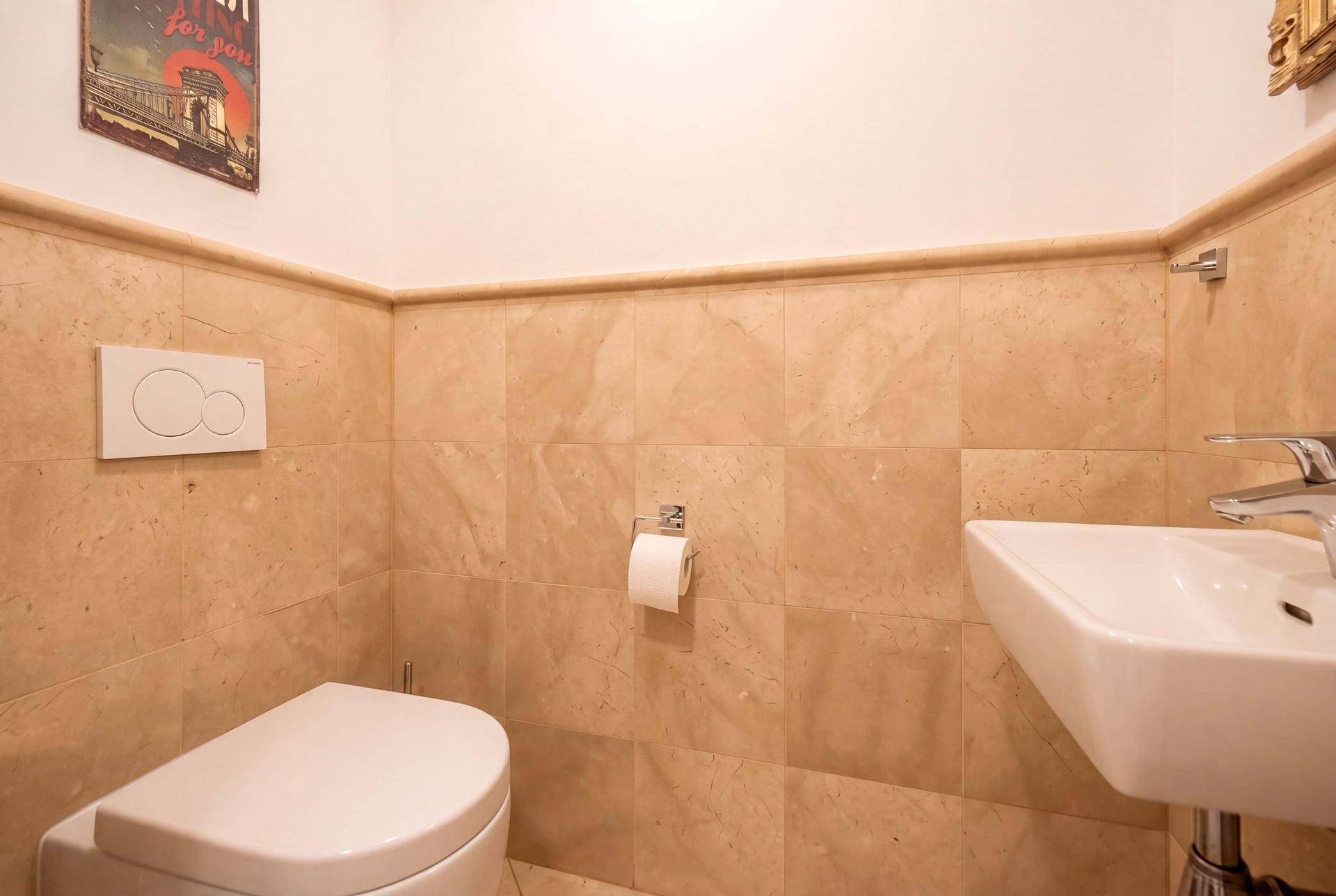 Kleines Gäste-WC mit Wand-WC und Waschbecken, modern gefliest.