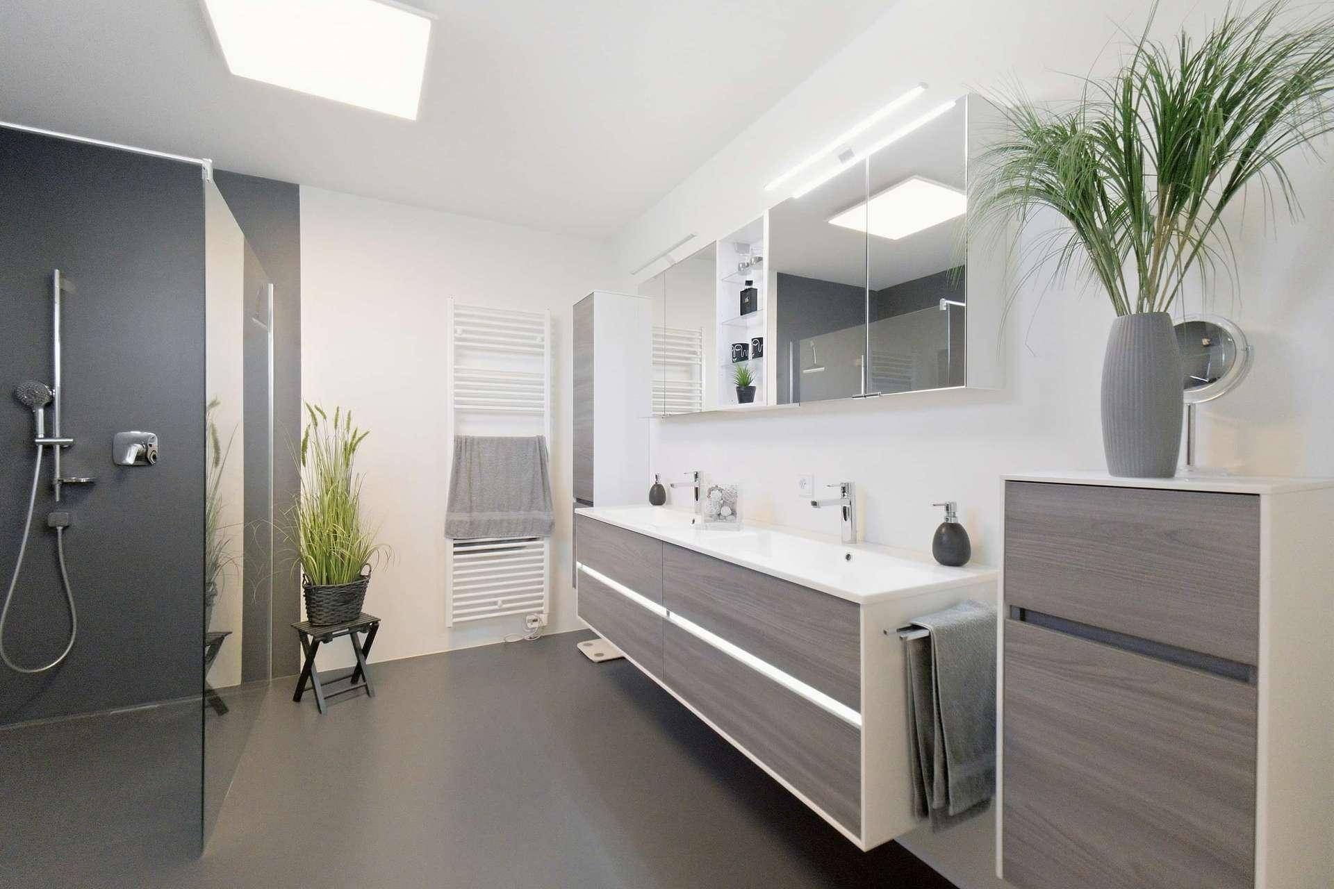 Elegantes Badezimmer mit Doppelwaschbecken, großer Dusche und beheiztem Handtuchhalter.