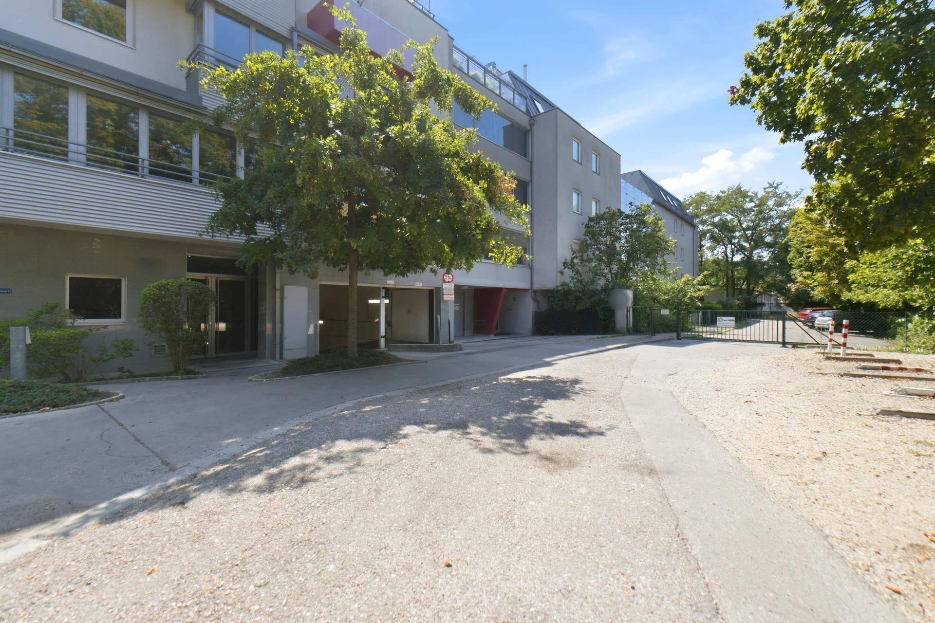 Modernes Mehrfamilienhaus mit gepflegter Außenanlage und Zufahrt zur Tiefgarage.