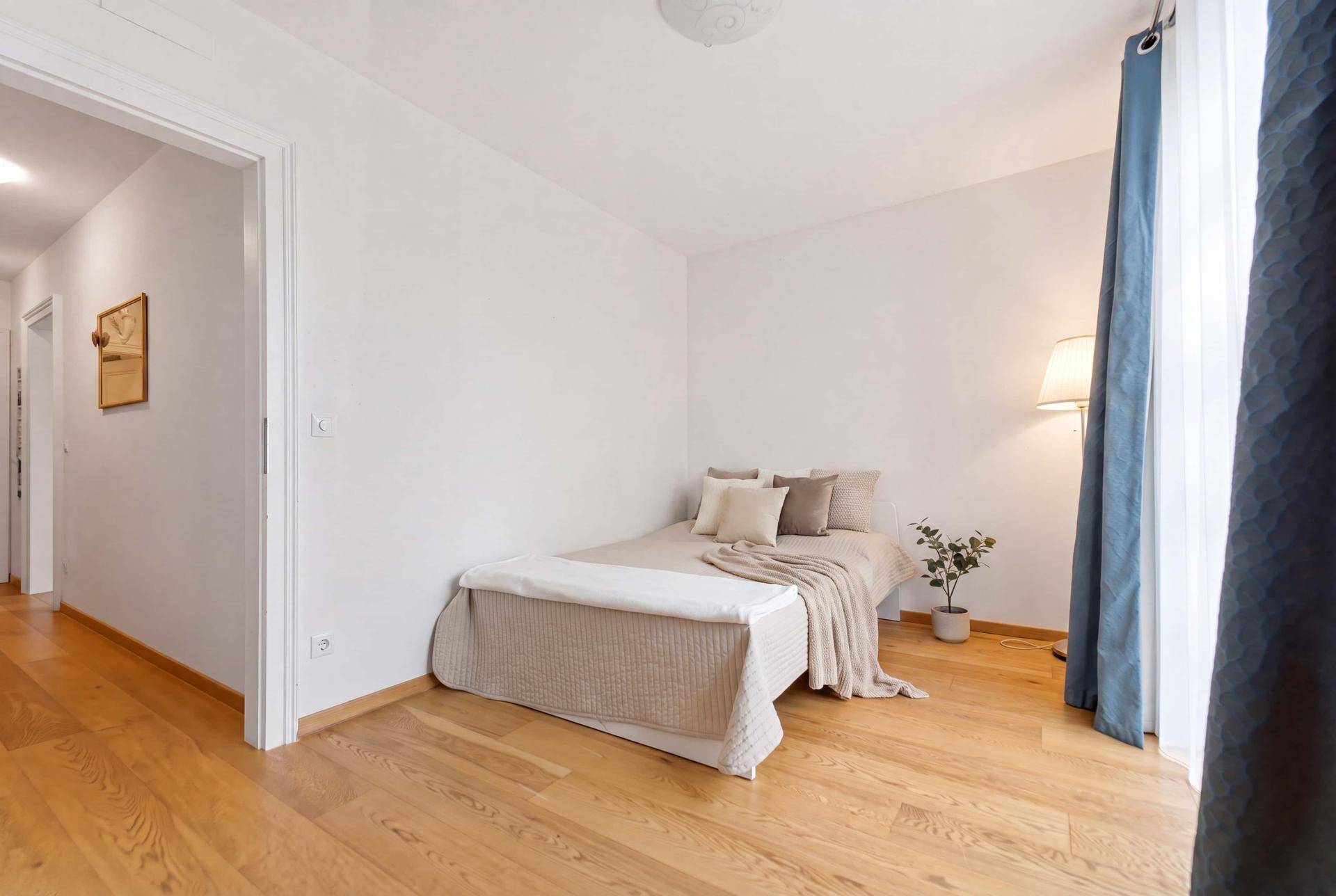 Gemütliches Schlafzimmer mit Holzboden, Bett und Stehlampe, hell und einladend.