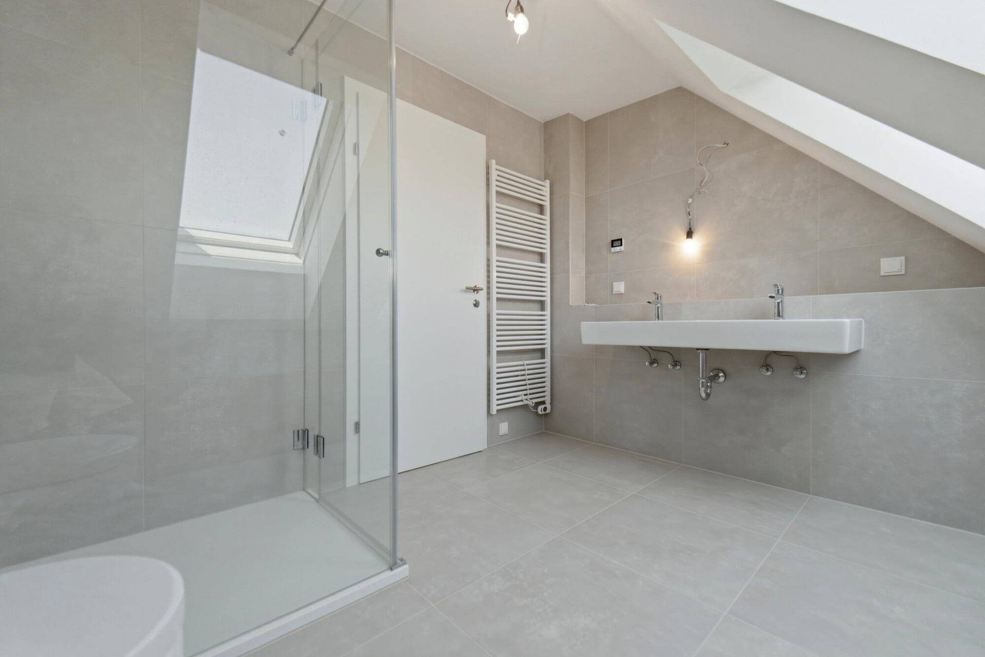 Modernes Badezimmer mit begehbarer Dusche, Doppelwaschbecken und beheiztem Handtuchhalter unter Dachschräge.