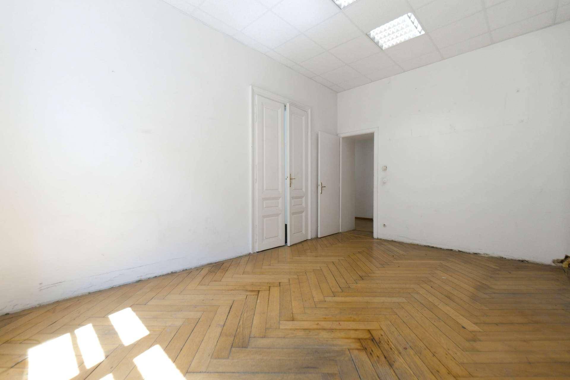 Heller, leerer Raum mit Parkettboden und eleganten Doppeltüren, vielseitig nutzbar.