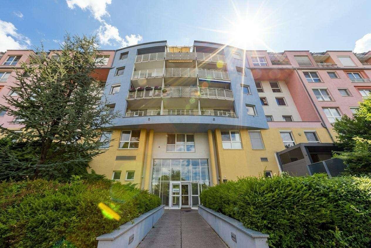 Farbenfrohes Mehrfamilienhaus mit vielen Balkonen und moderner Architektur unter blauem Himmel.