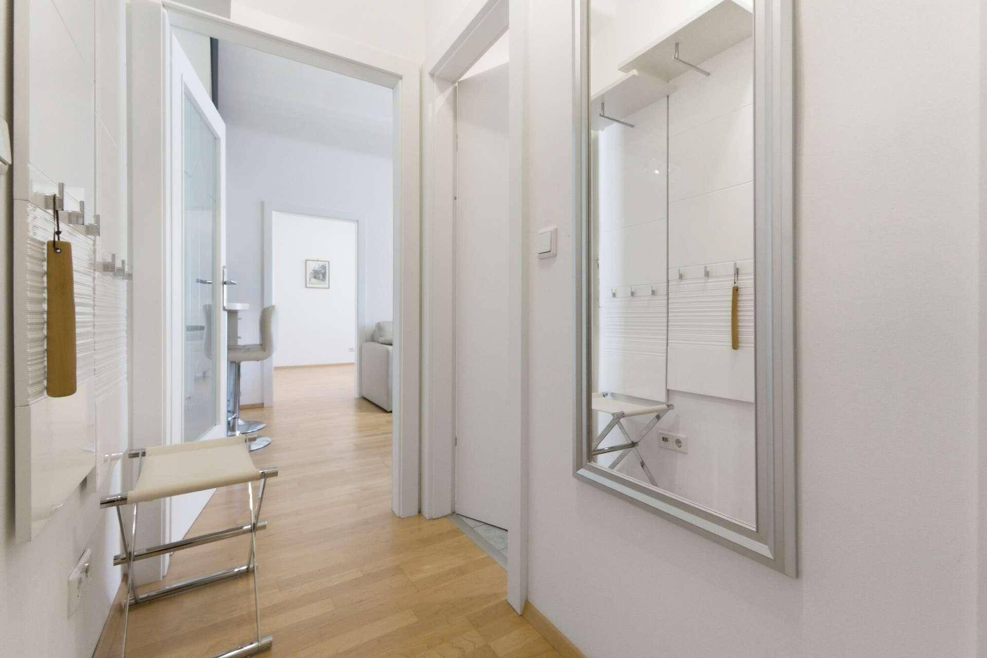 Heller Eingangsbereich mit Spiegel, Garderobe und Blick in den Wohnbereich.