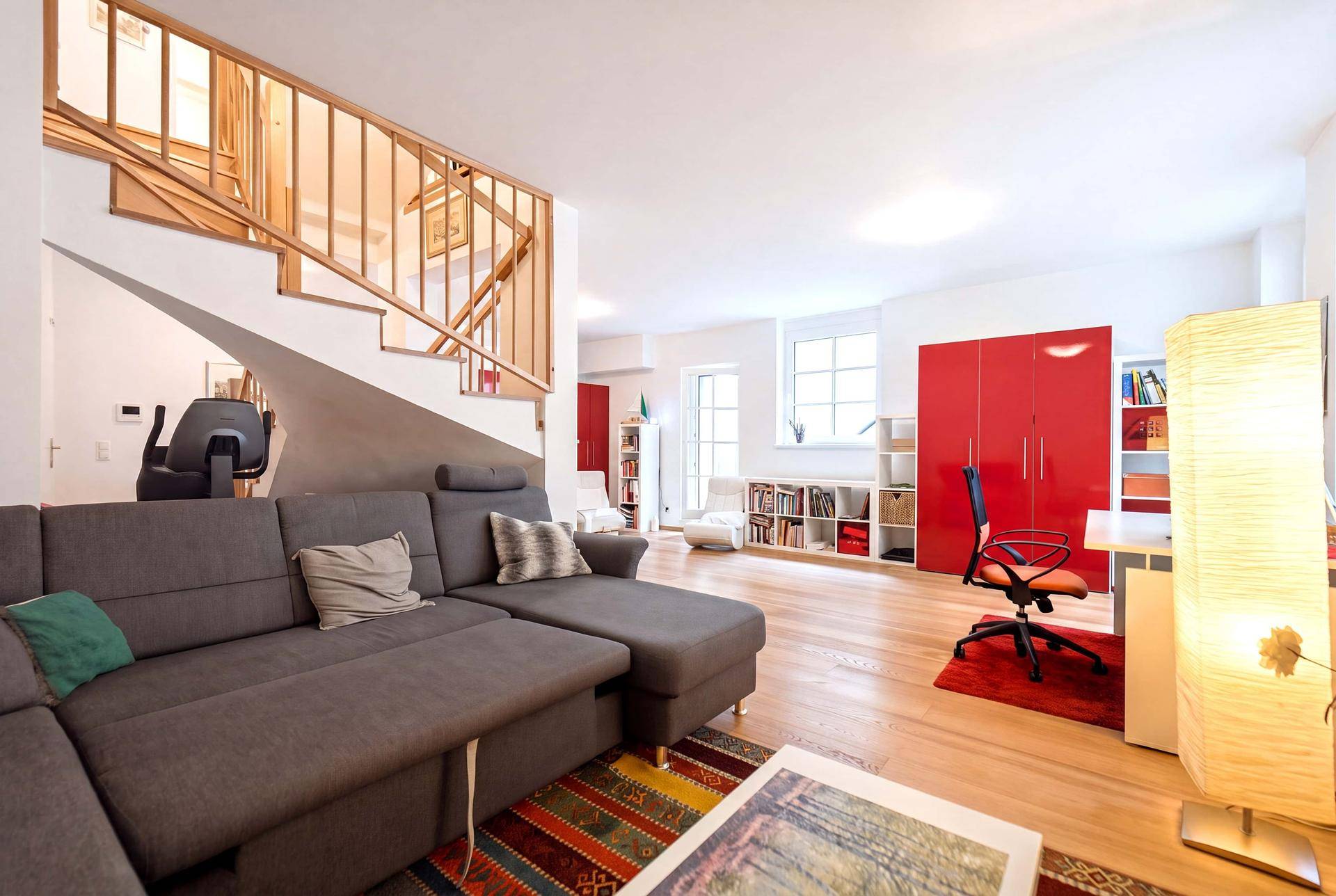 Heller Wohnbereich mit bequemer Couch, Holzboden und Treppe, ideal für Entspannung und Arbeit.