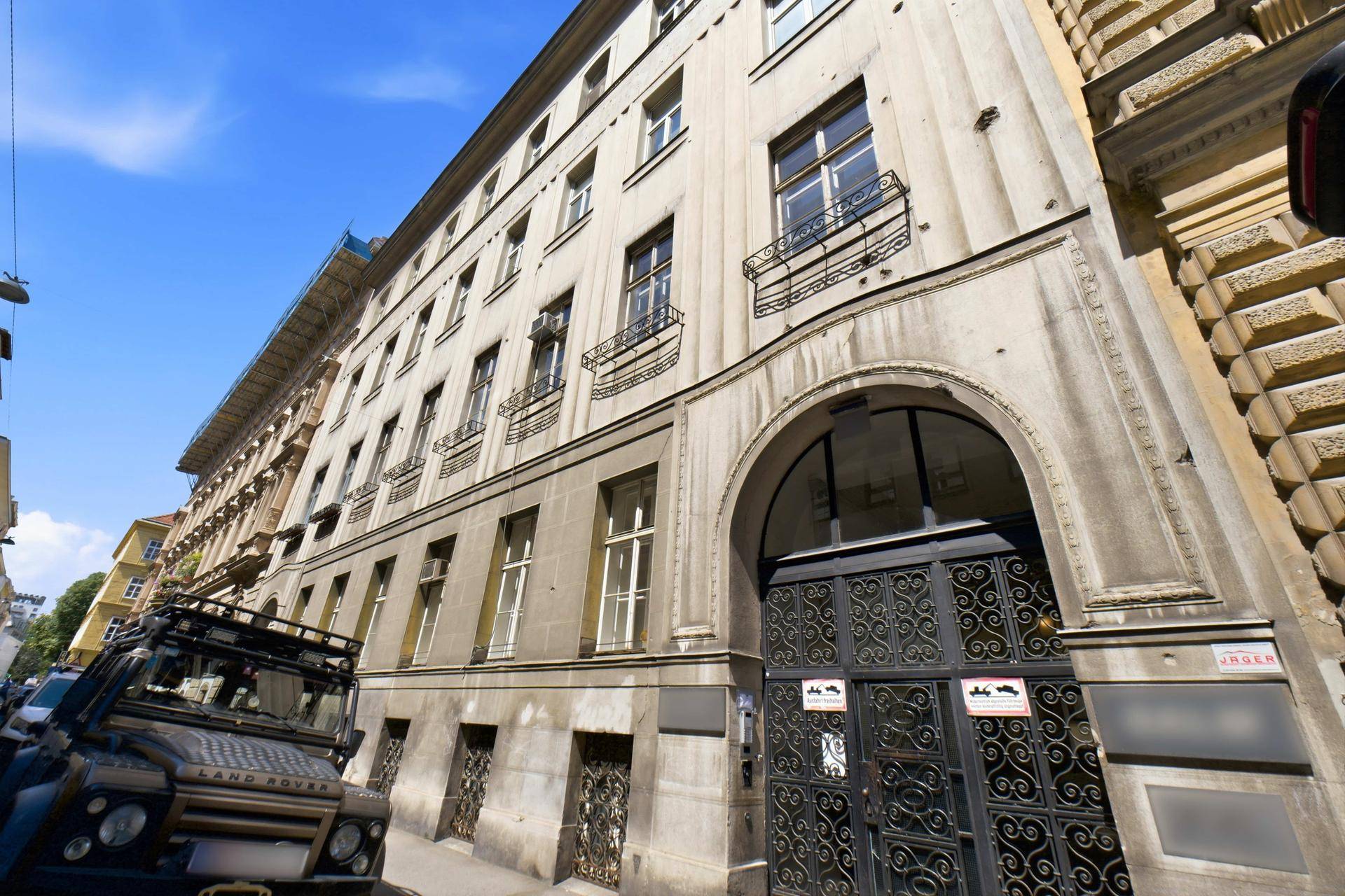 Historisches Gebäude mit klassischer Fassade und vielen Fenstern an einer belebten Straße.