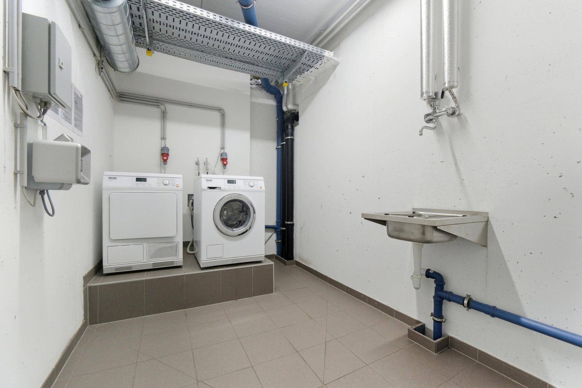 Praktischer Hauswirtschaftsraum mit Waschmaschine, Trockner und Waschbecken.