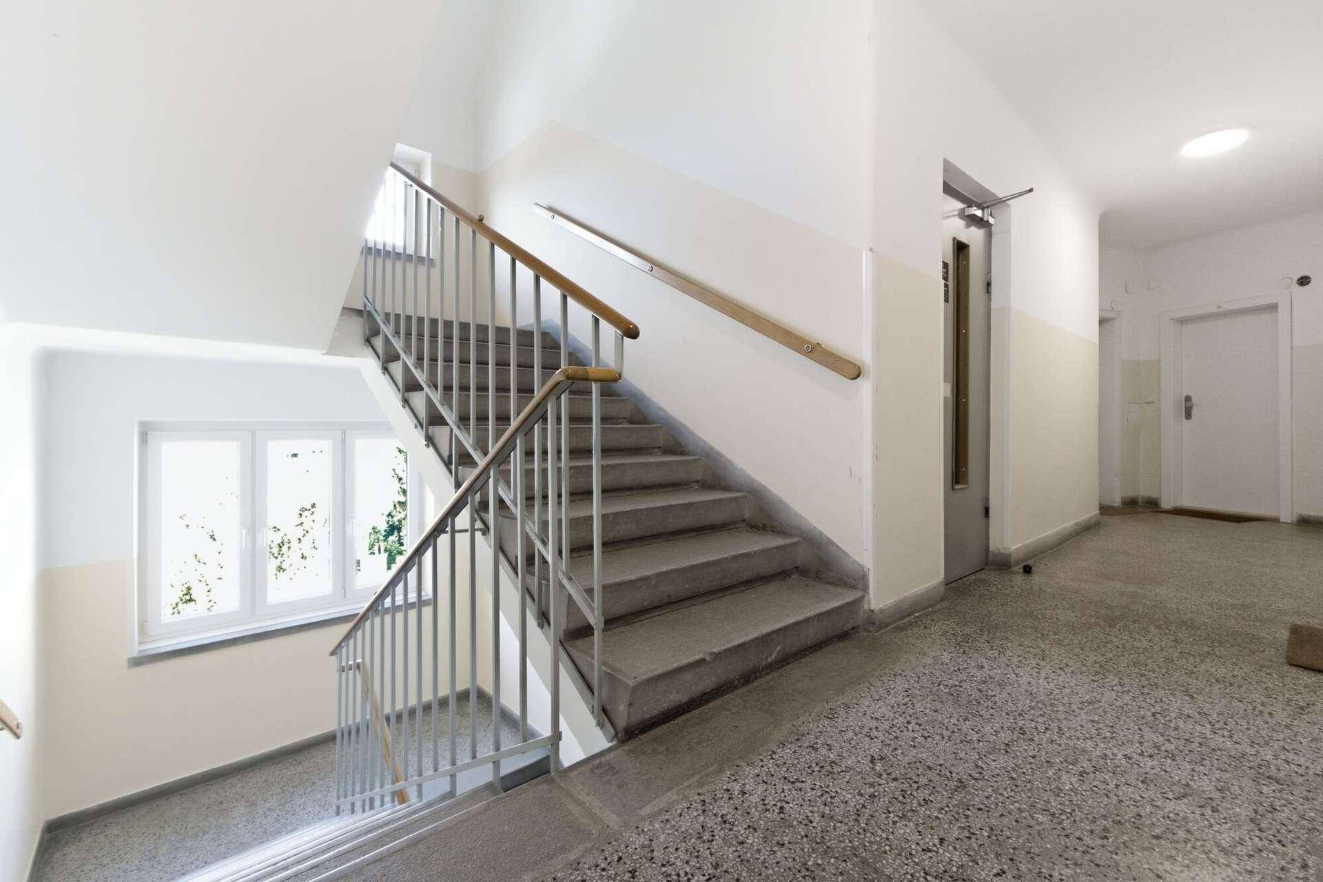Geräumiges Treppenhaus mit Steinstufen, Metallgeländer und natürlichem Lichteinfall.