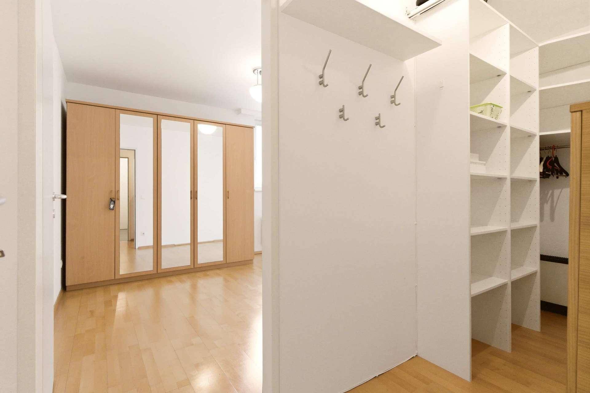 Praktischer begehbarer Kleiderschrank mit Regalen und Blick auf das angrenzende Schlafzimmer.
