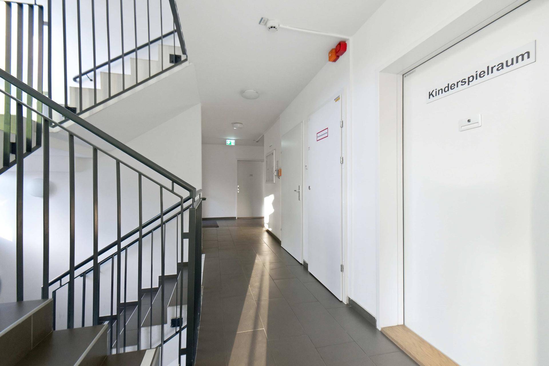 Heller Flur im Gebäude mit Zugang zu verschiedenen Räumen und einem Kinderspielzimmer.